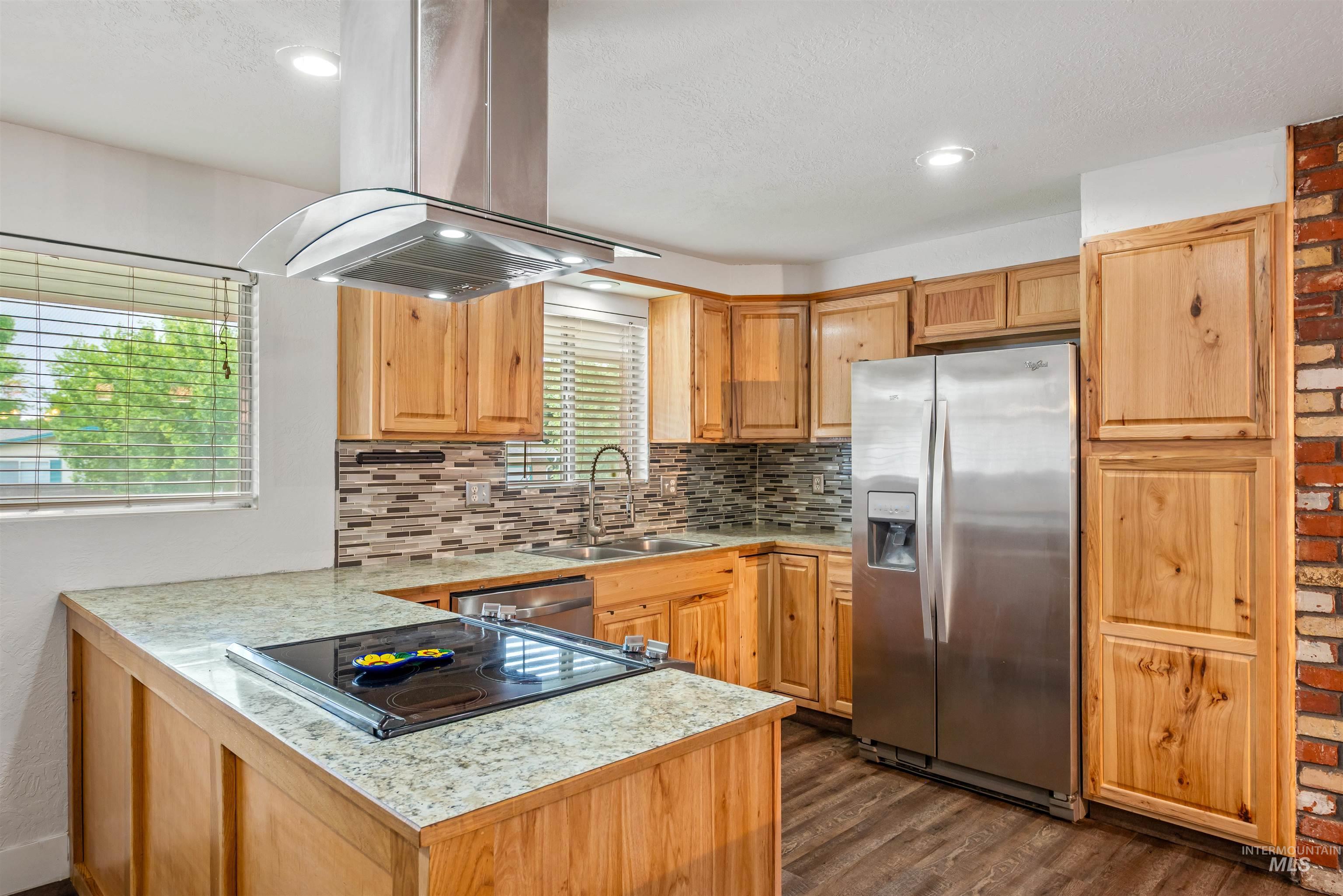 Kitchen with appliances with stainless steel finishes, decorative backsplash, island range hood, dark wood-style flooring, and recessed lighting