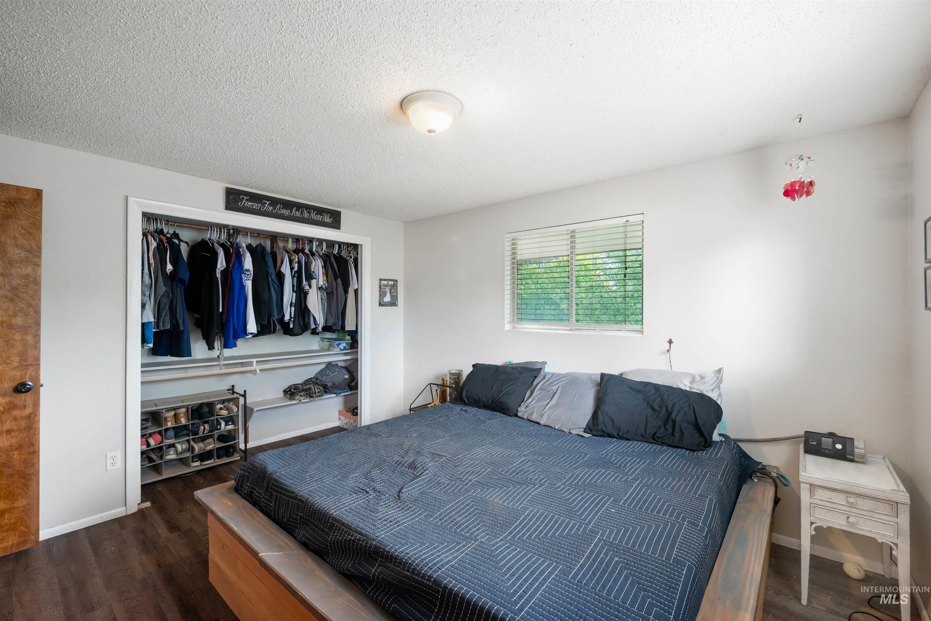 Bedroom with wood finished floors, a textured ceiling, and a closet