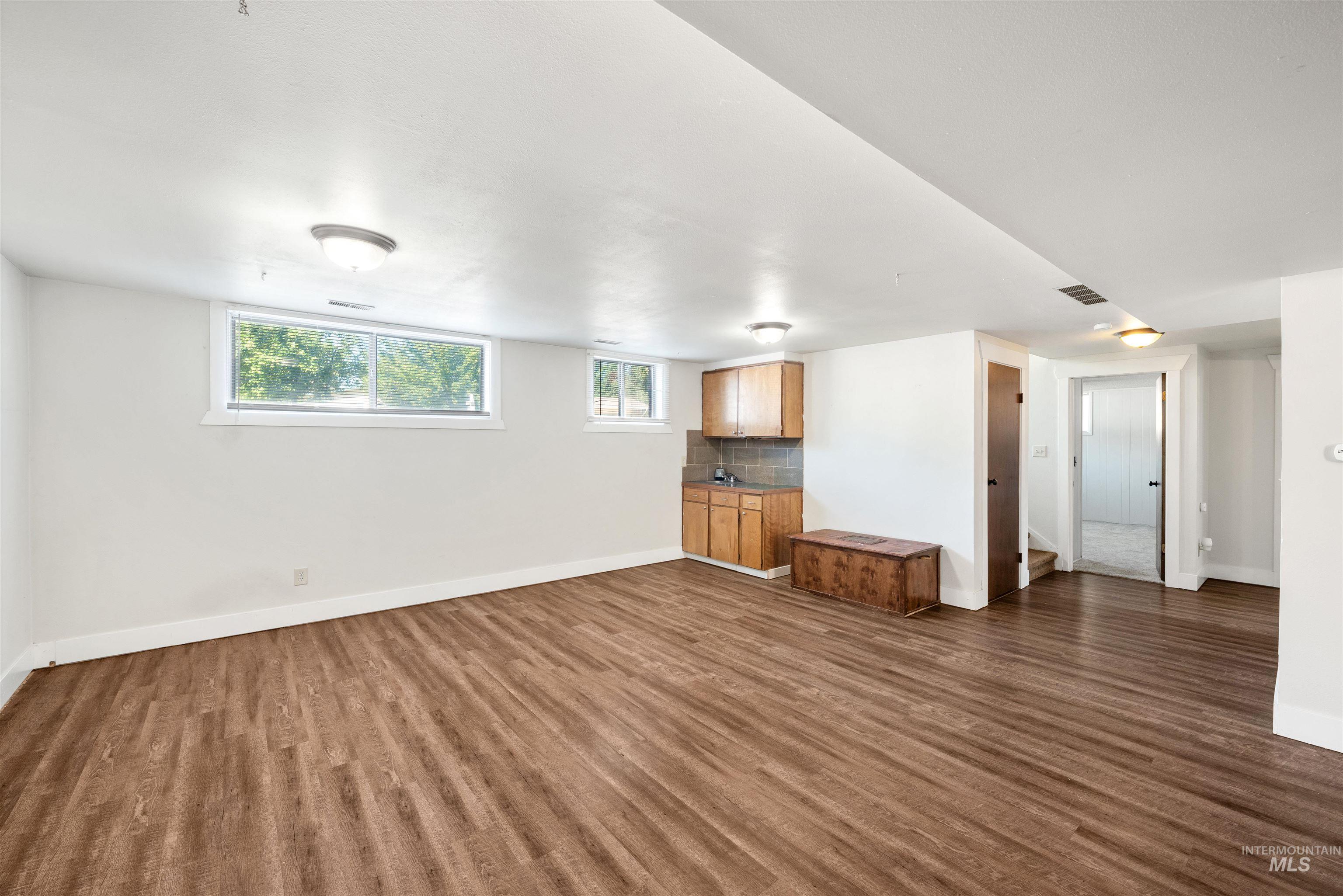 Unfurnished living room featuring baseboards and dark wood finished floors