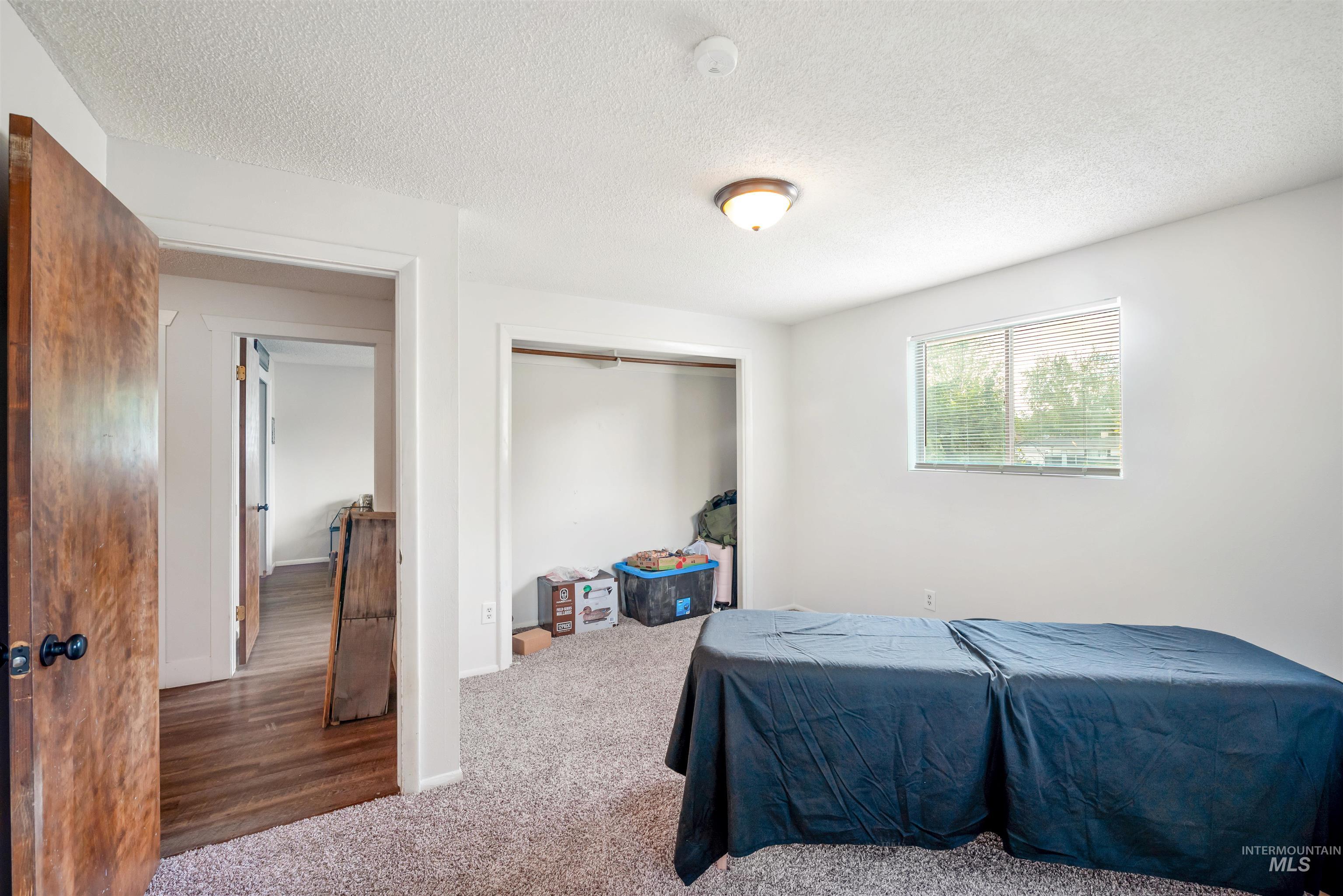 Bedroom with carpet floors, a textured ceiling, and a closet