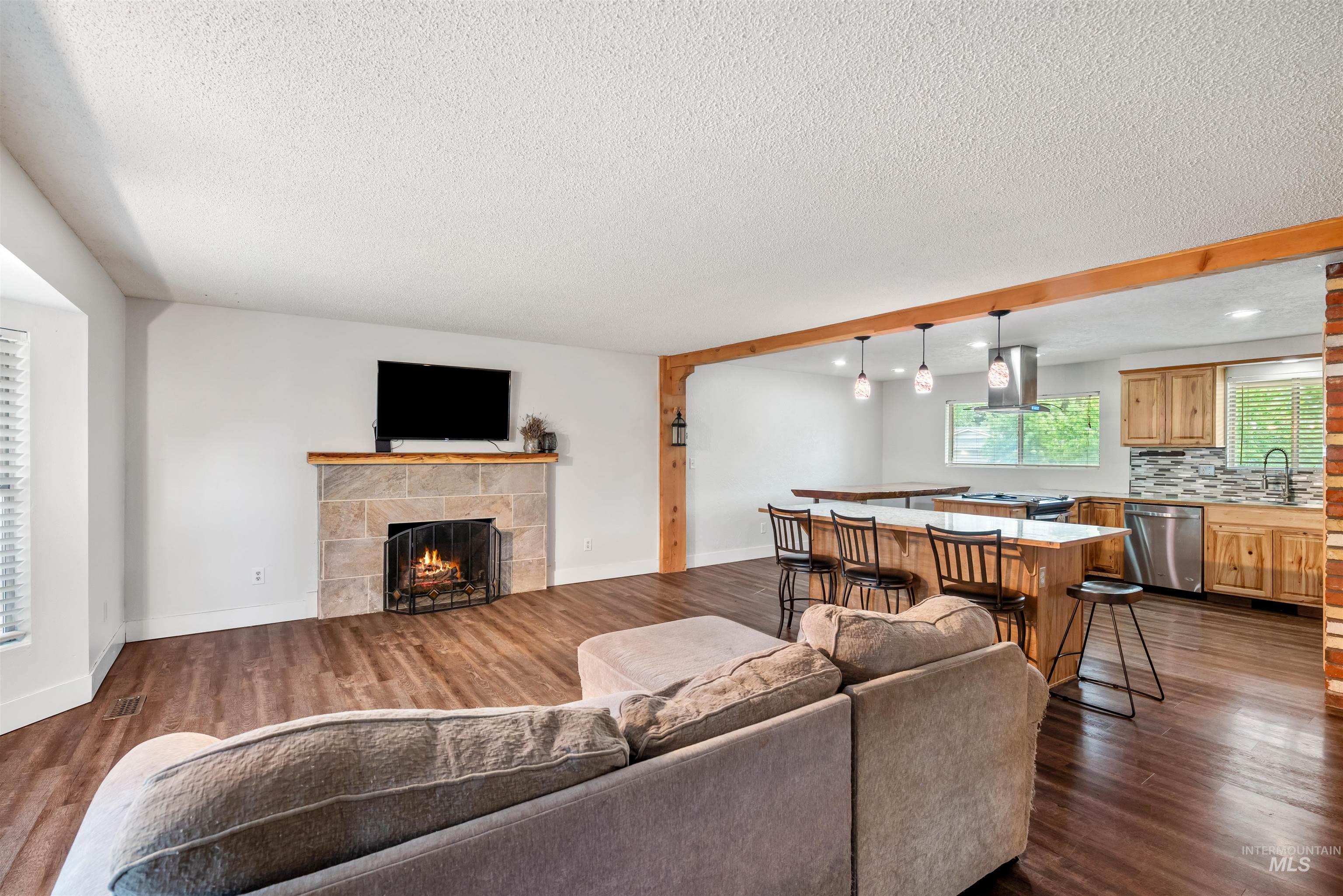 Living area with a tiled fireplace, dark wood-style flooring, a textured ceiling, and recessed lighting