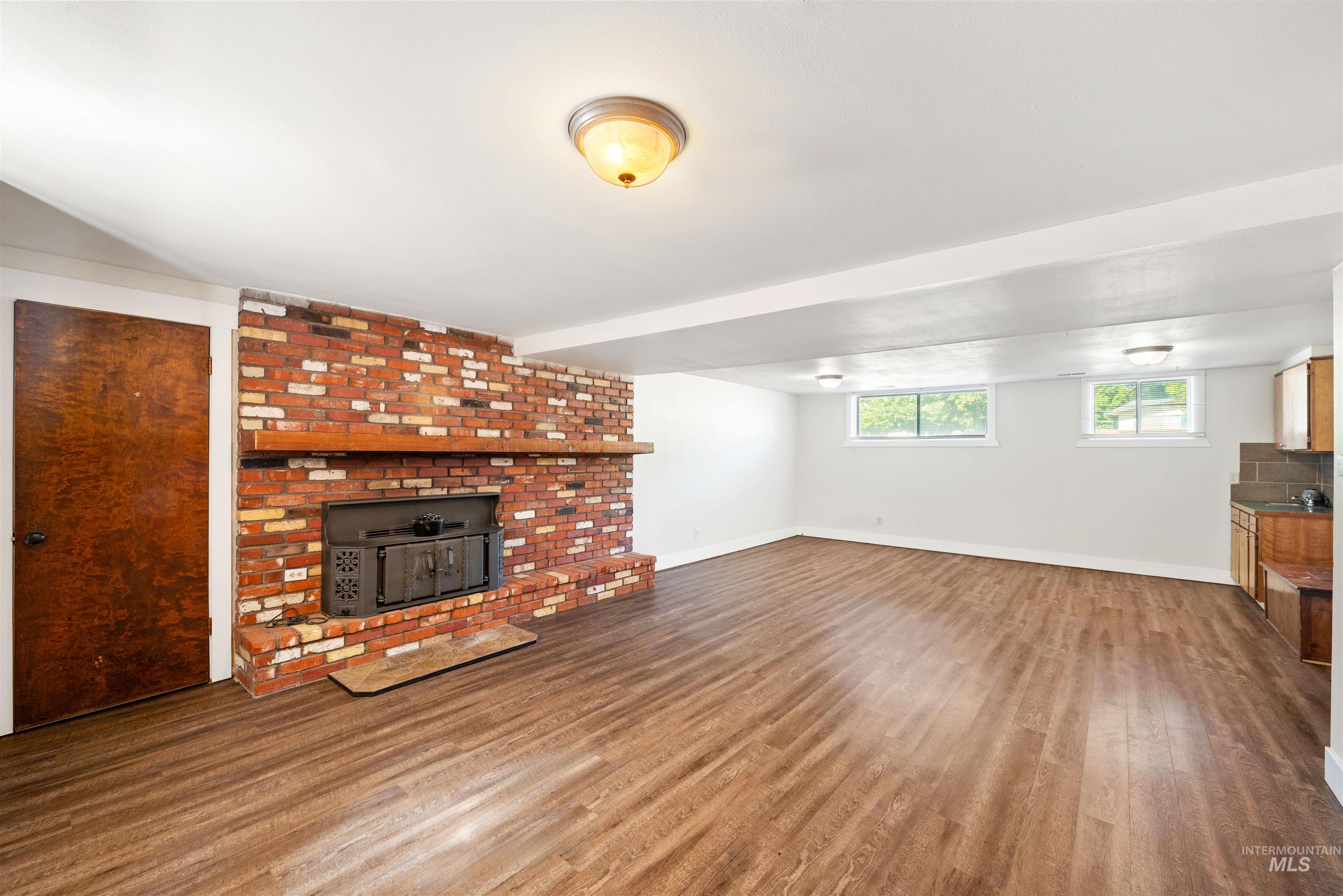 Unfurnished living room with wood finished floors and a wood stove