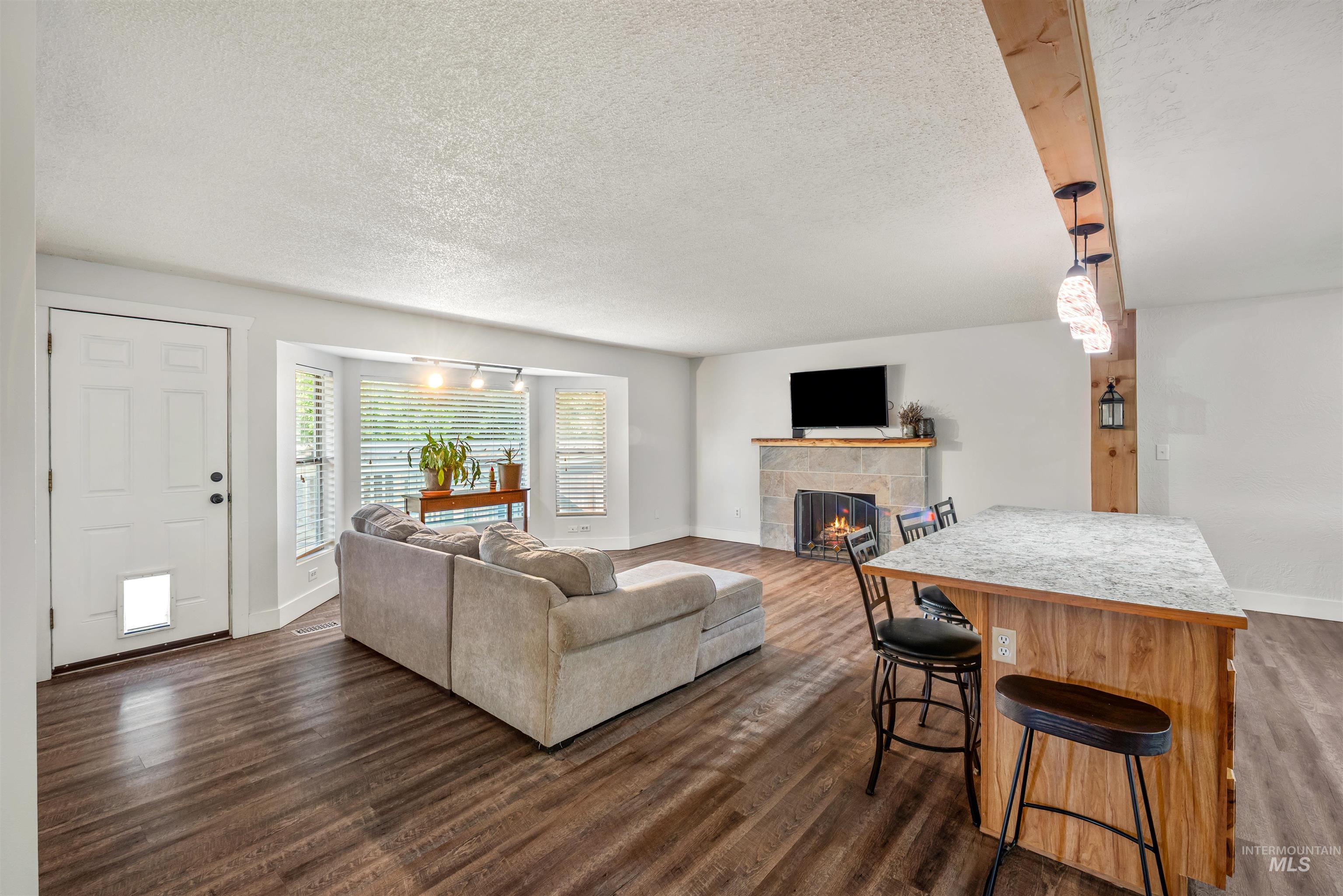 Living room featuring a textured ceiling, a tiled fireplace, and dark wood-style floors