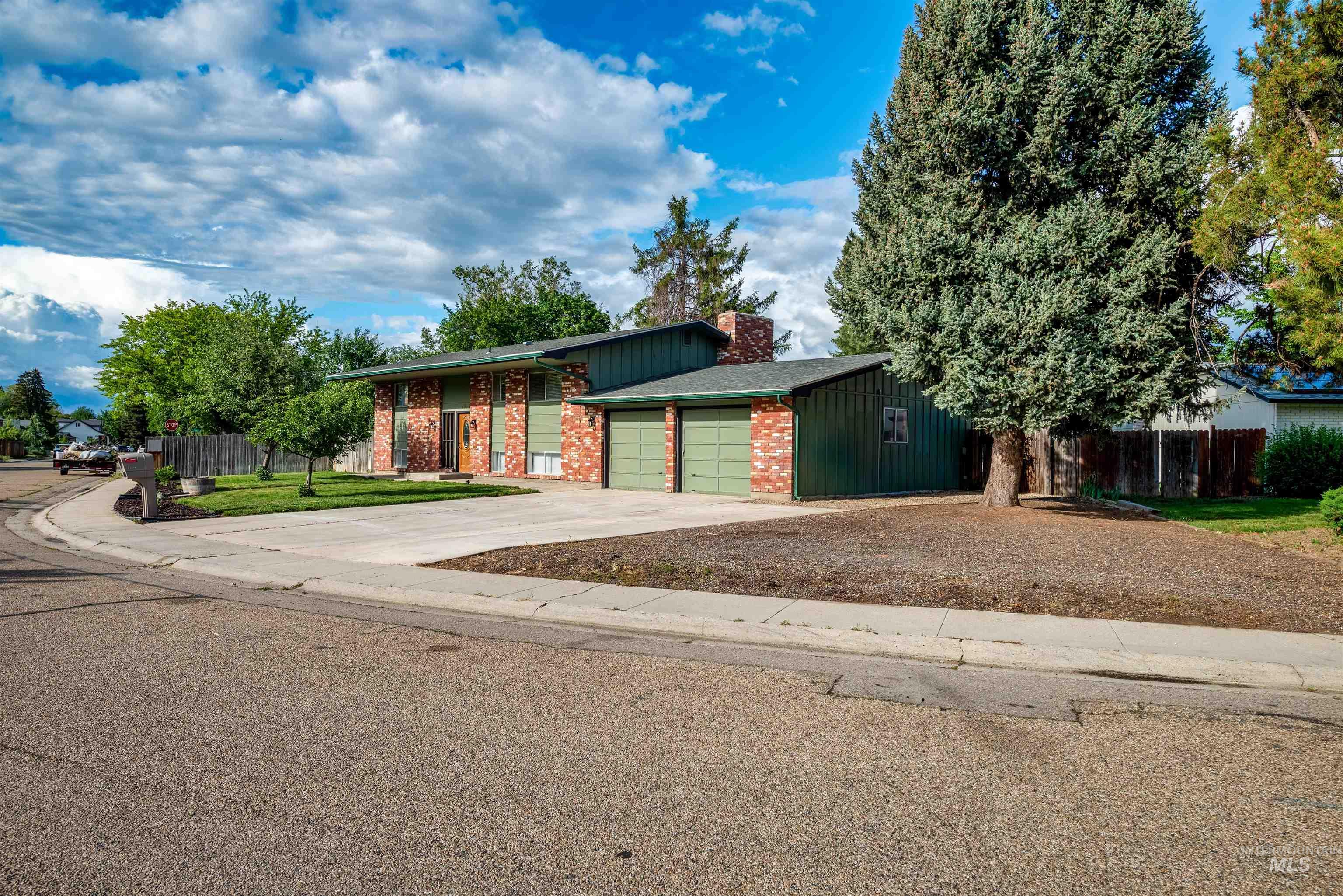 View of front of property featuring driveway, a chimney, an attached garage, and brick siding