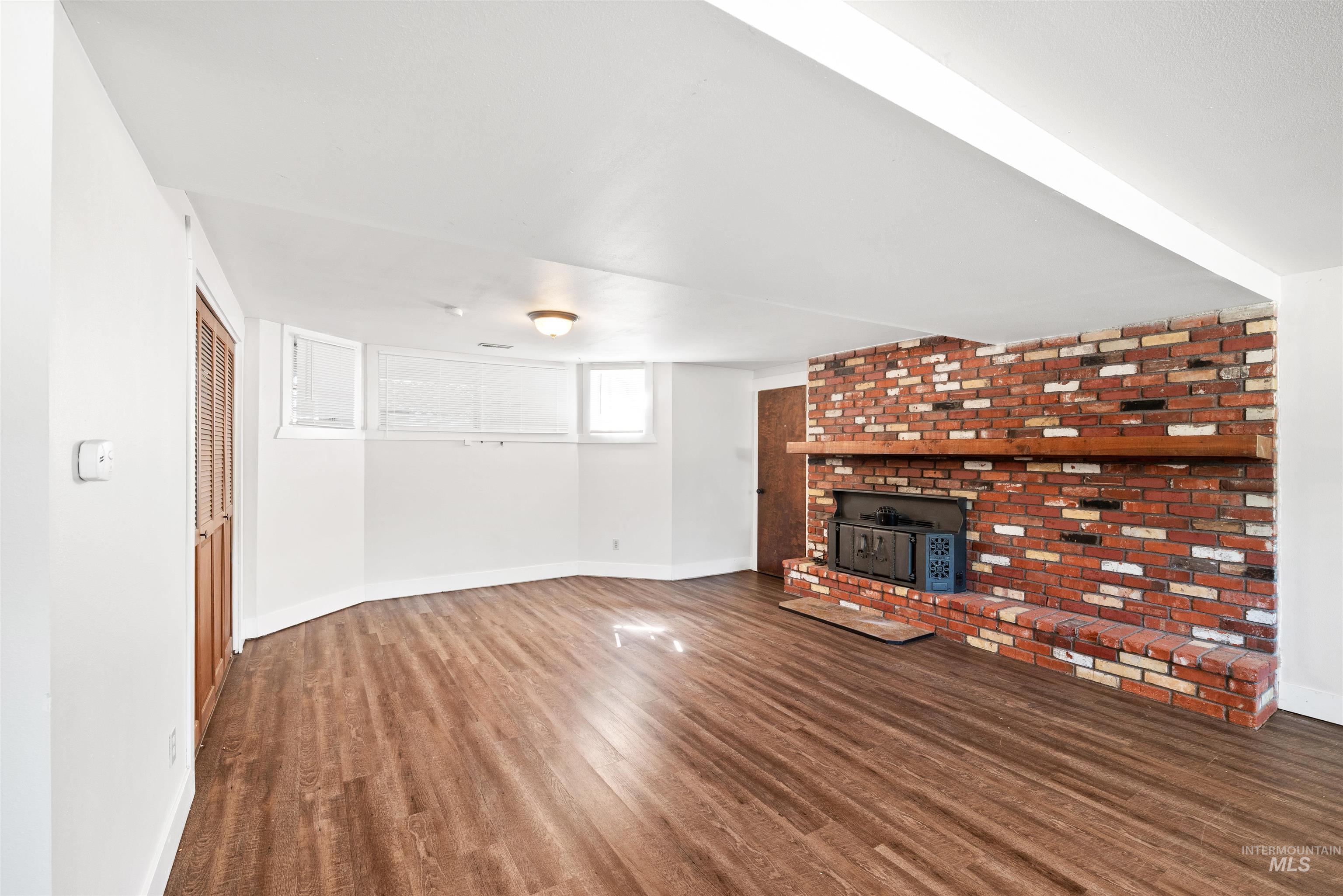 Unfurnished living room with a wood stove and dark wood-type flooring