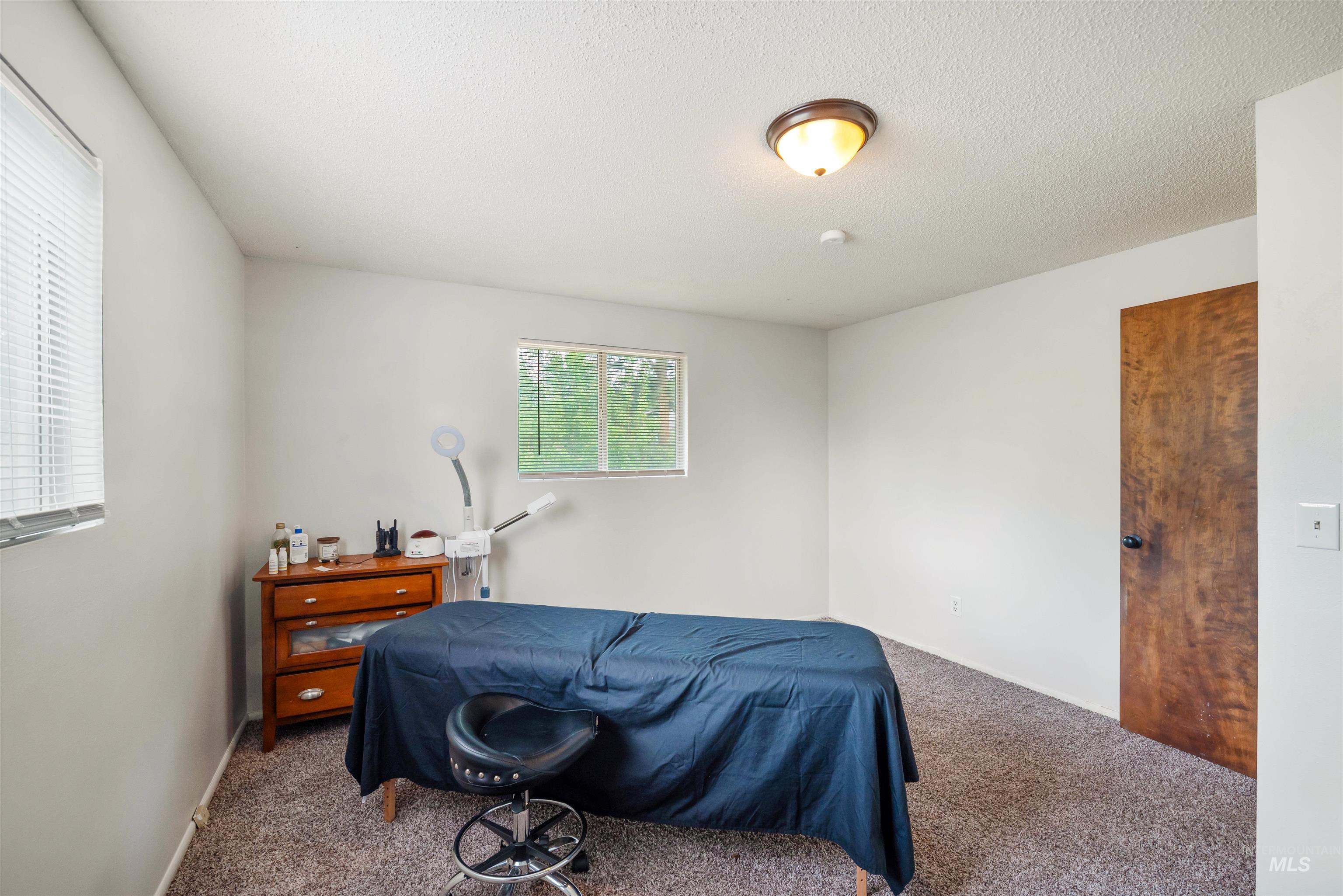 Carpeted bedroom featuring a textured ceiling and baseboards