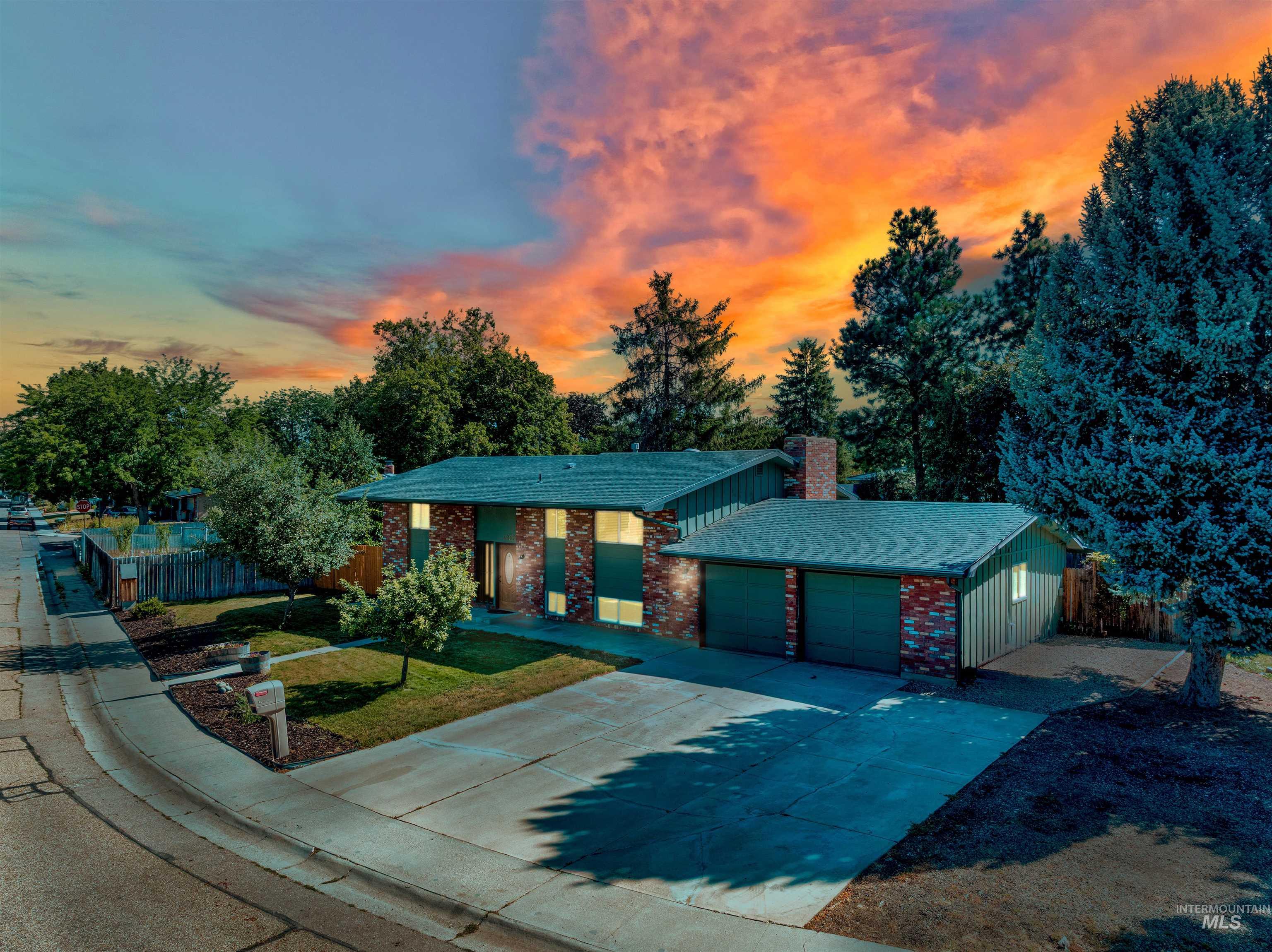 Mid-century home featuring brick siding, driveway, a chimney, a garage, and roof with shingles