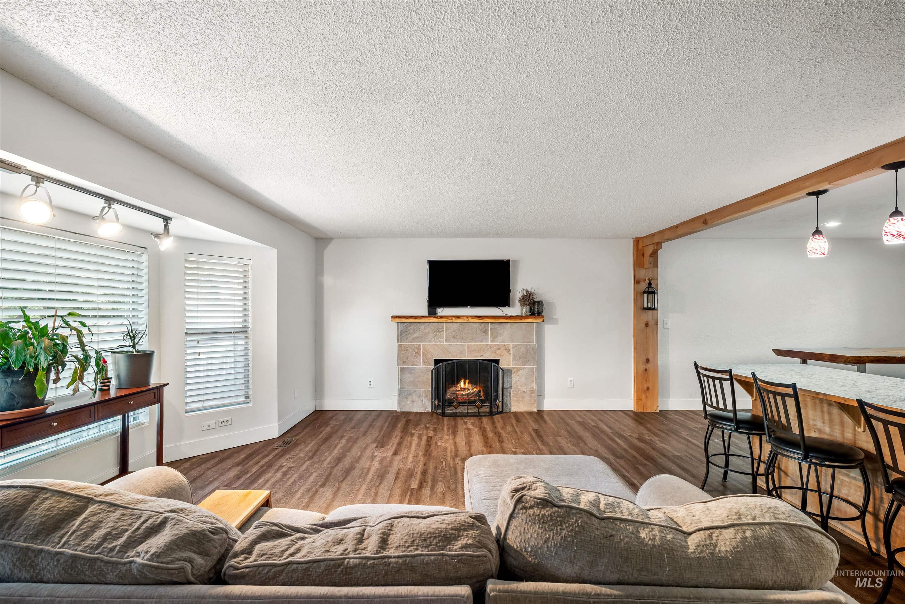 Living room with a textured ceiling, wood finished floors, and a tile fireplace