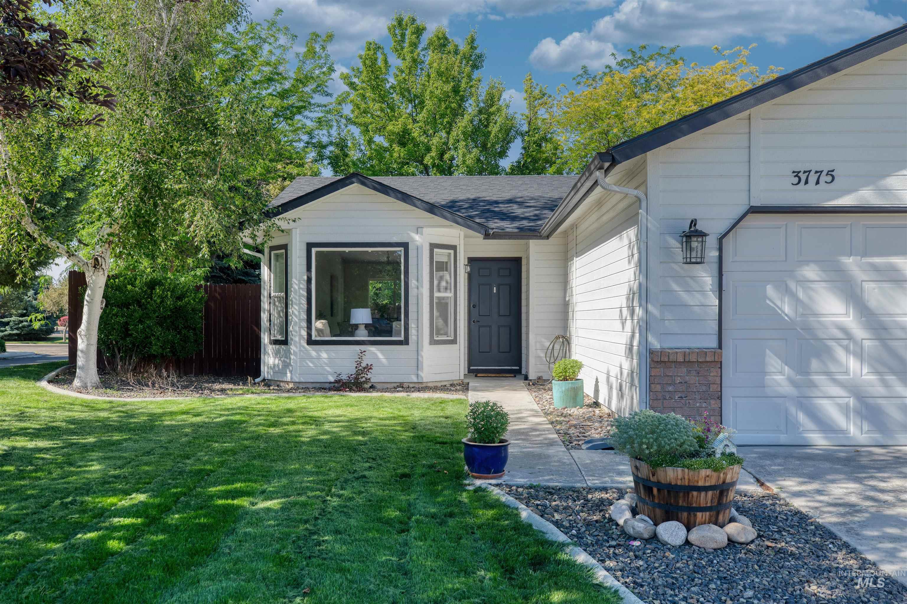 Contemporary single-story residence featuring a two-car garage, dark gray multi-pane front door, and a bay window with black trim