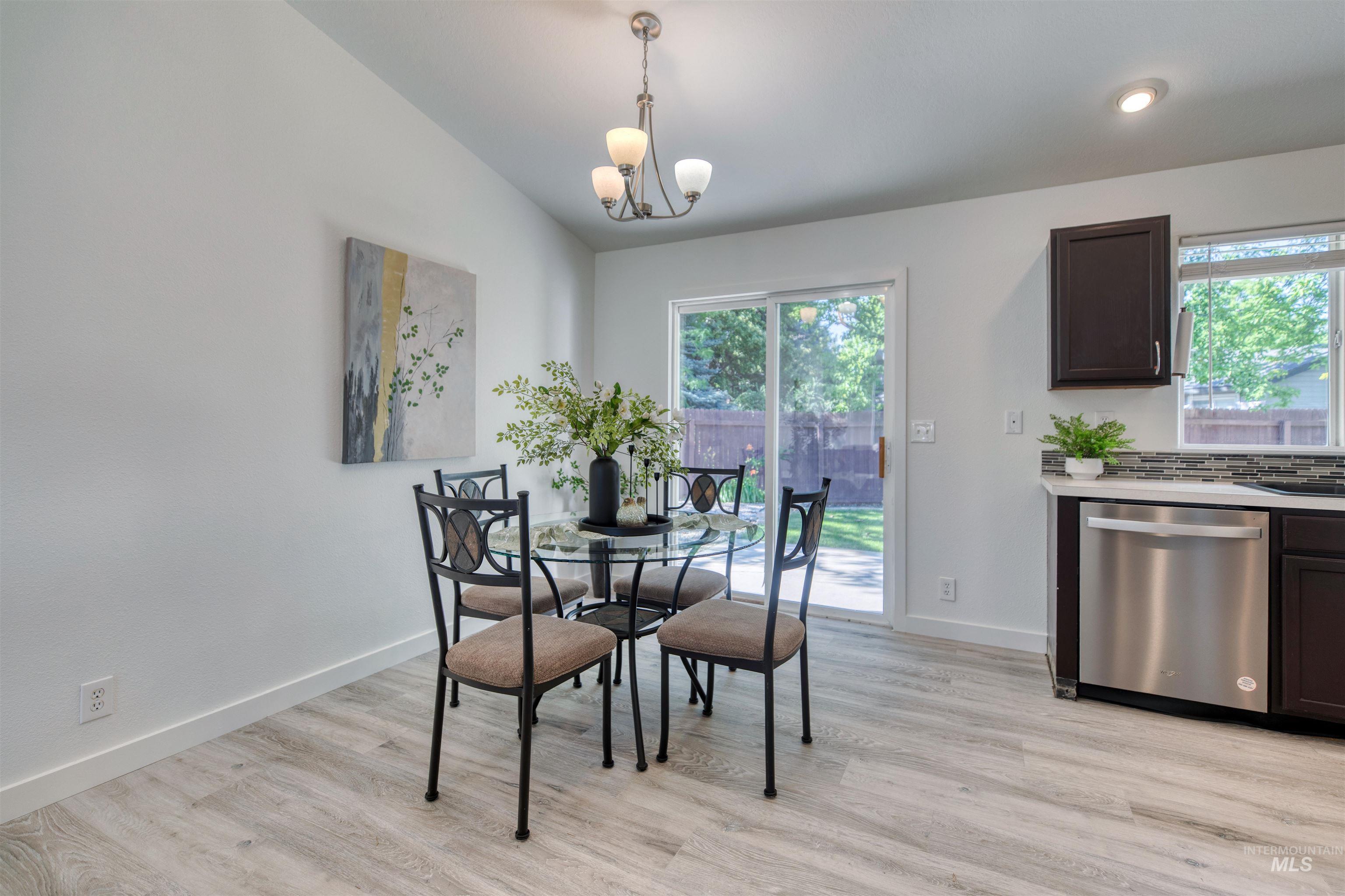 Dining area featuring vaulted ceilings, light wood-finish flooring, and a sliding glass door to the exterior