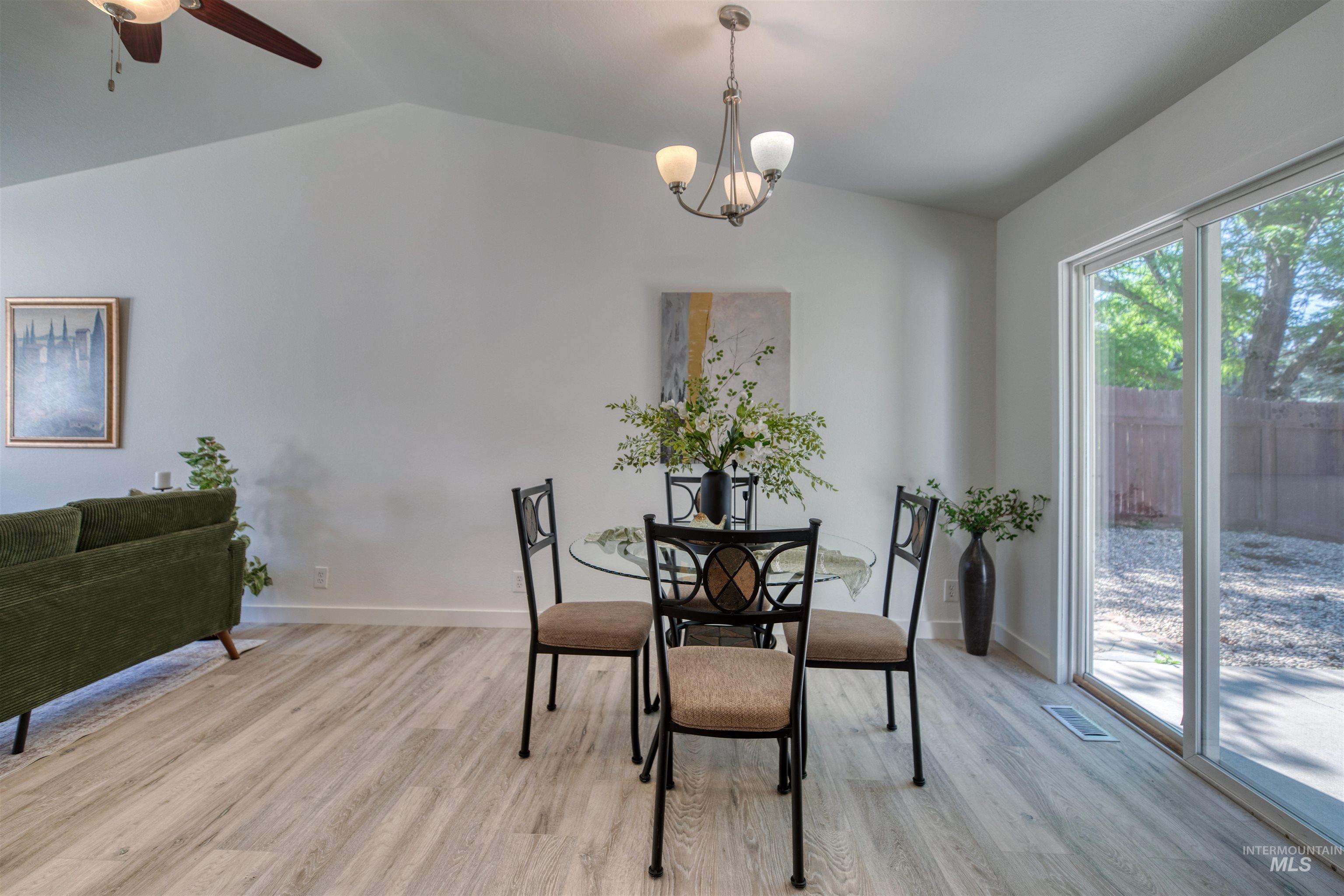 Dining area with wood-finish flooring, vaulted ceiling, and a modern chandelier