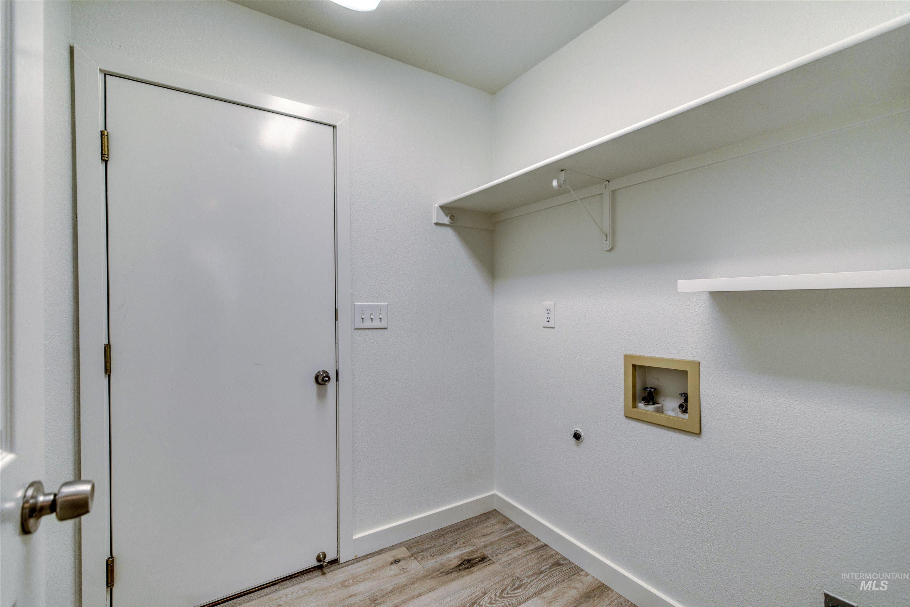 Utility space featuring wood-finish flooring, white walls, and built-in shelving