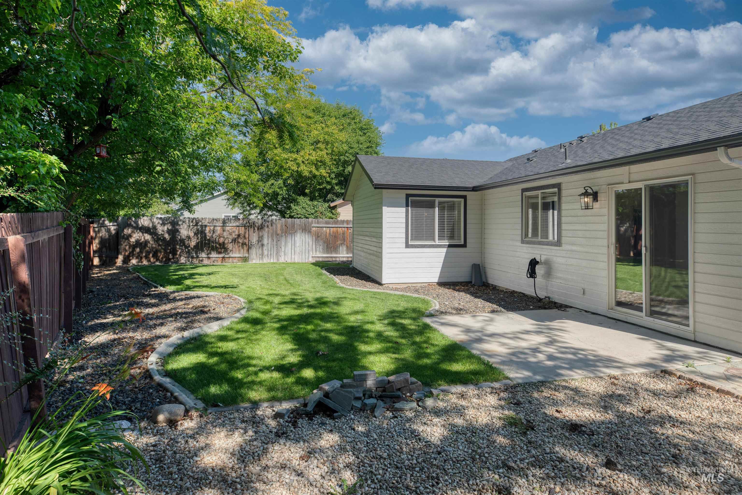 Expansive backyard featuring a manicured lawn, concrete patio, and mature trees