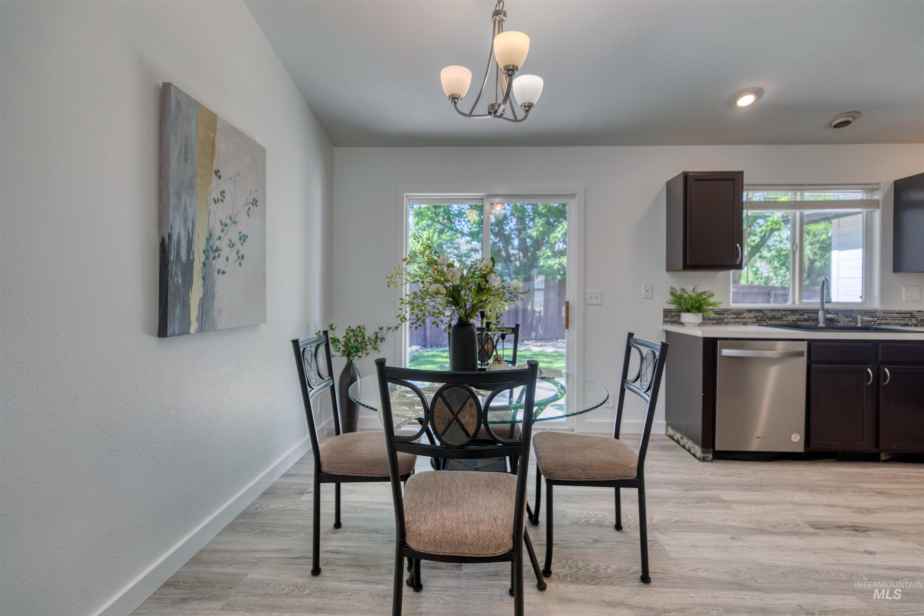 Dining area featuring wood-finish flooring, a sliding glass door, and a multi-bulb chandelier