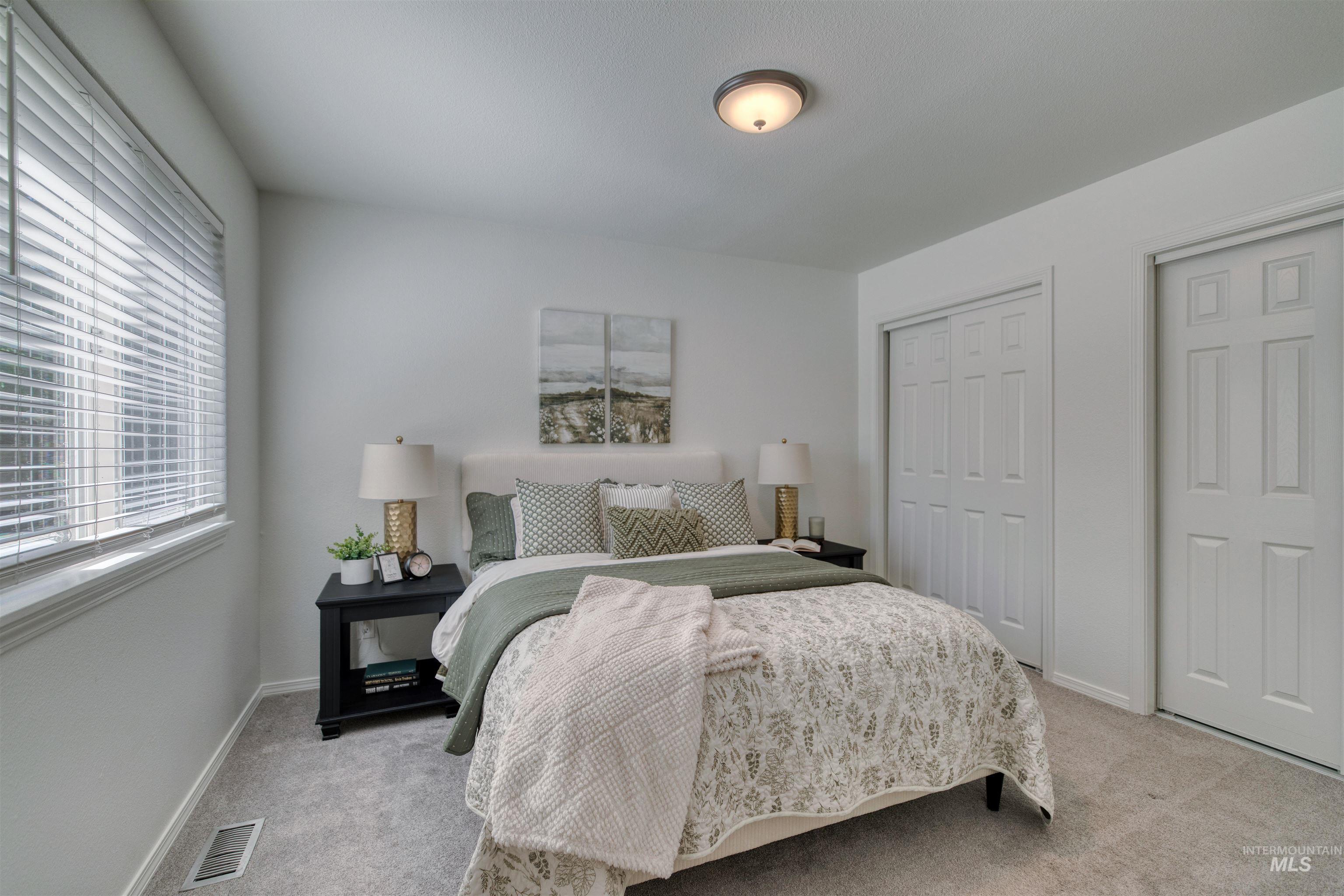 Carpeted bedroom featuring multiple closets with bi-fold and standard paneled doors, a window with blinds, and a flush-mount ceiling light fixture