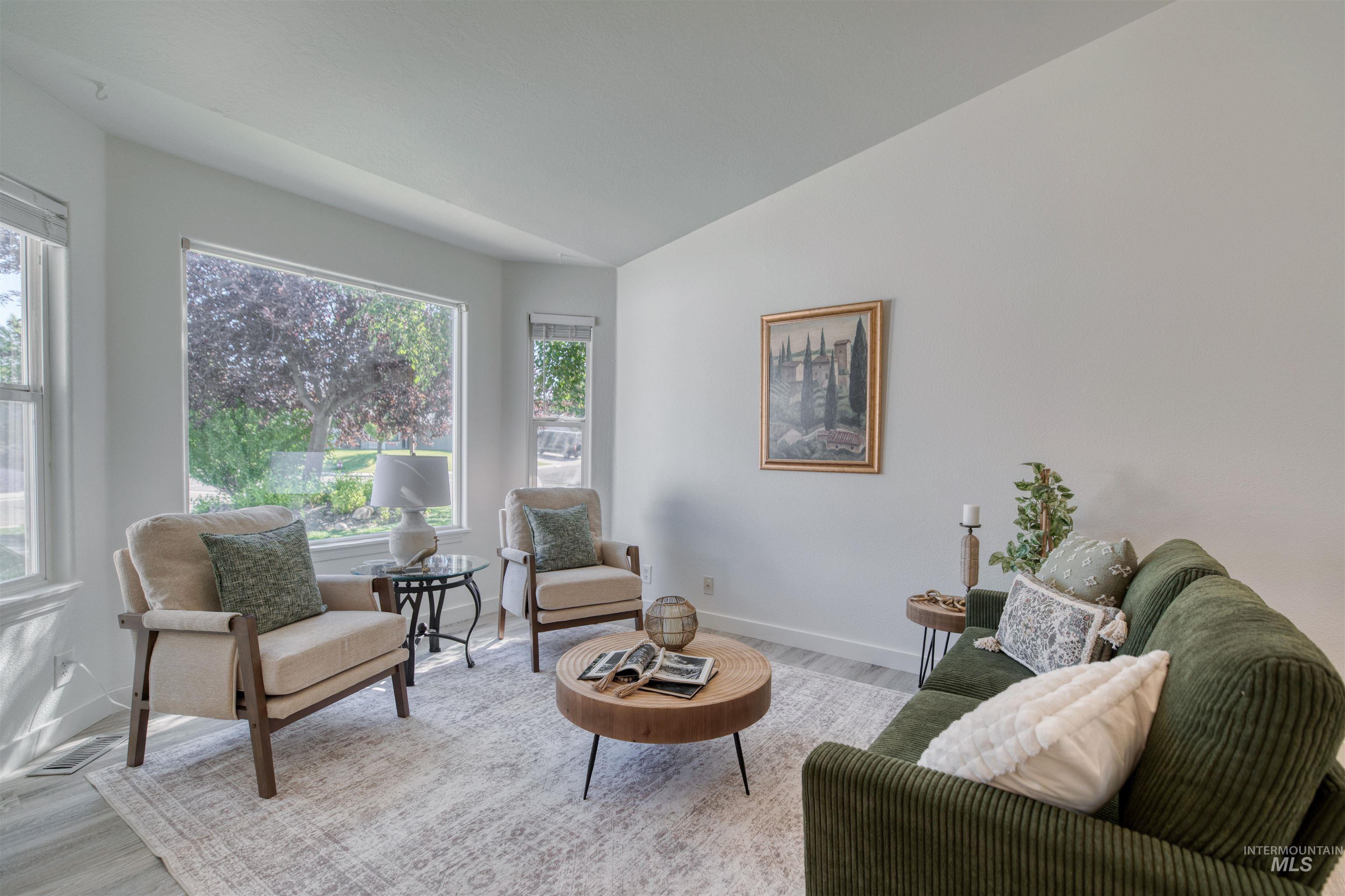Spacious living area featuring large windows, vaulted ceilings, and light wood-finish flooring