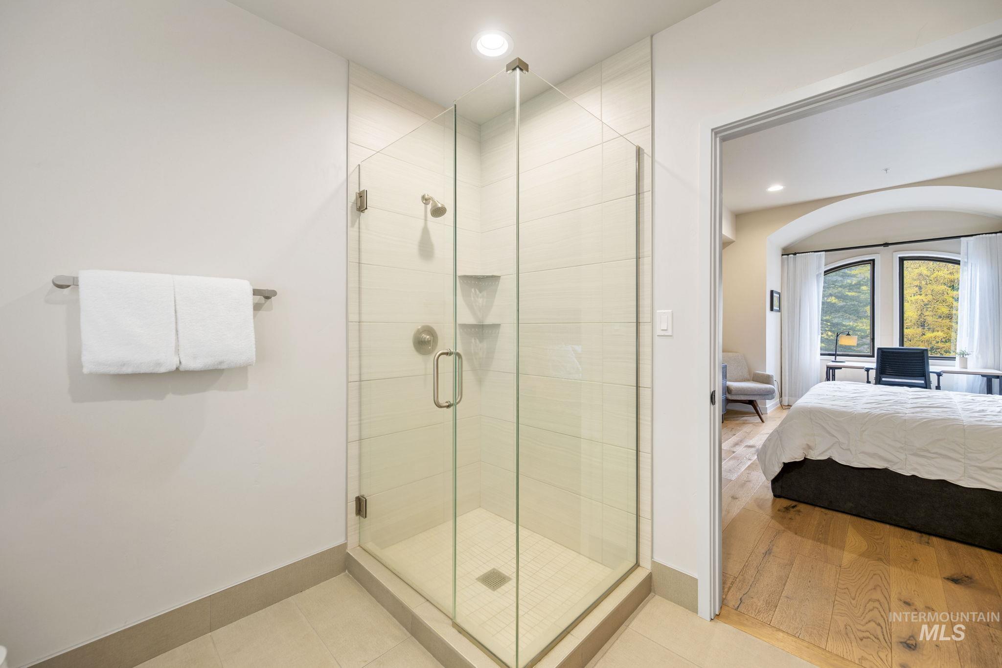 Bathroom with a shower stall, recessed lighting, connected bathroom, and light tile patterned floors