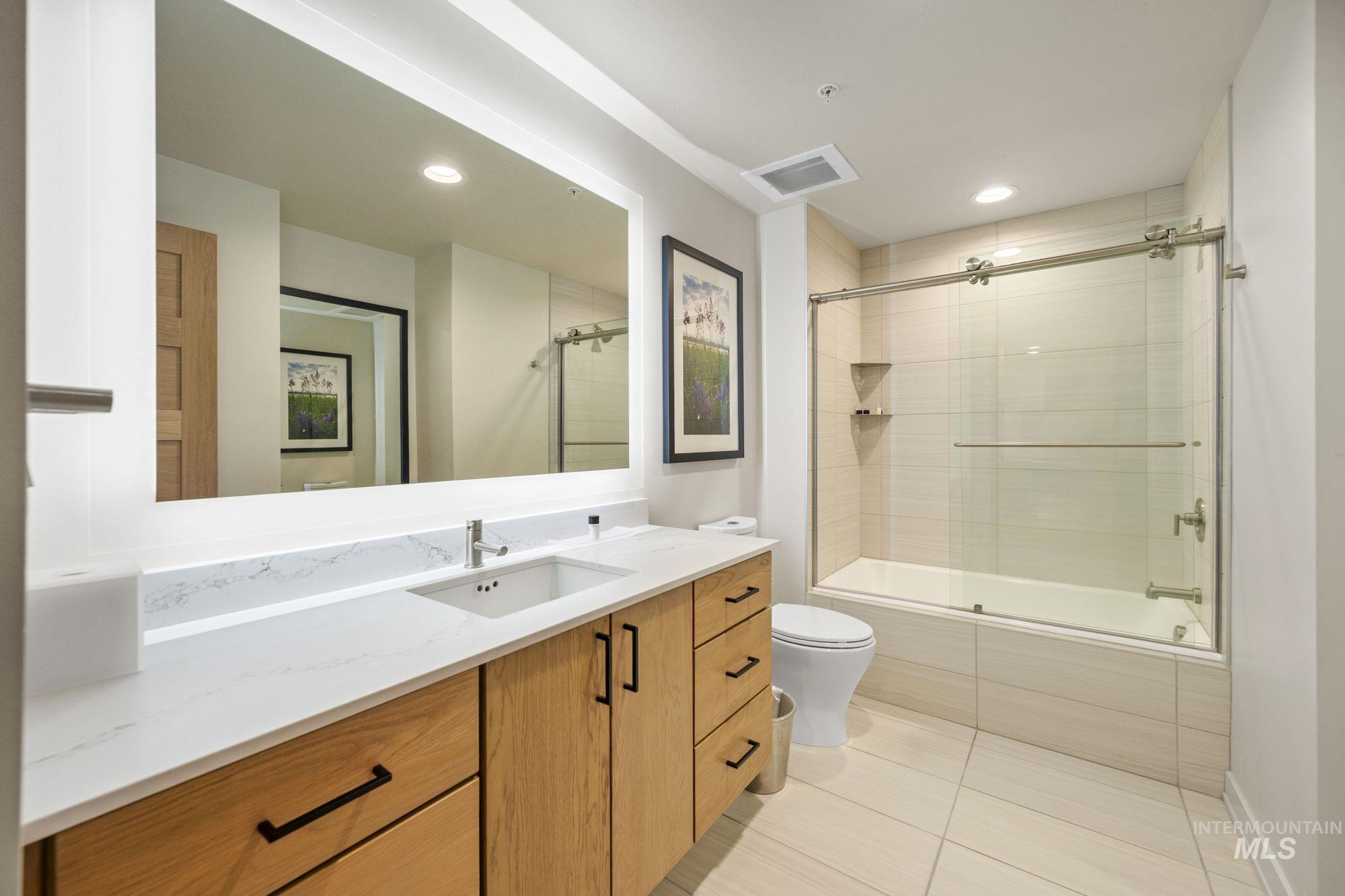 Full bath with vanity, light tile patterned floors, tiled shower / bath, and recessed lighting
