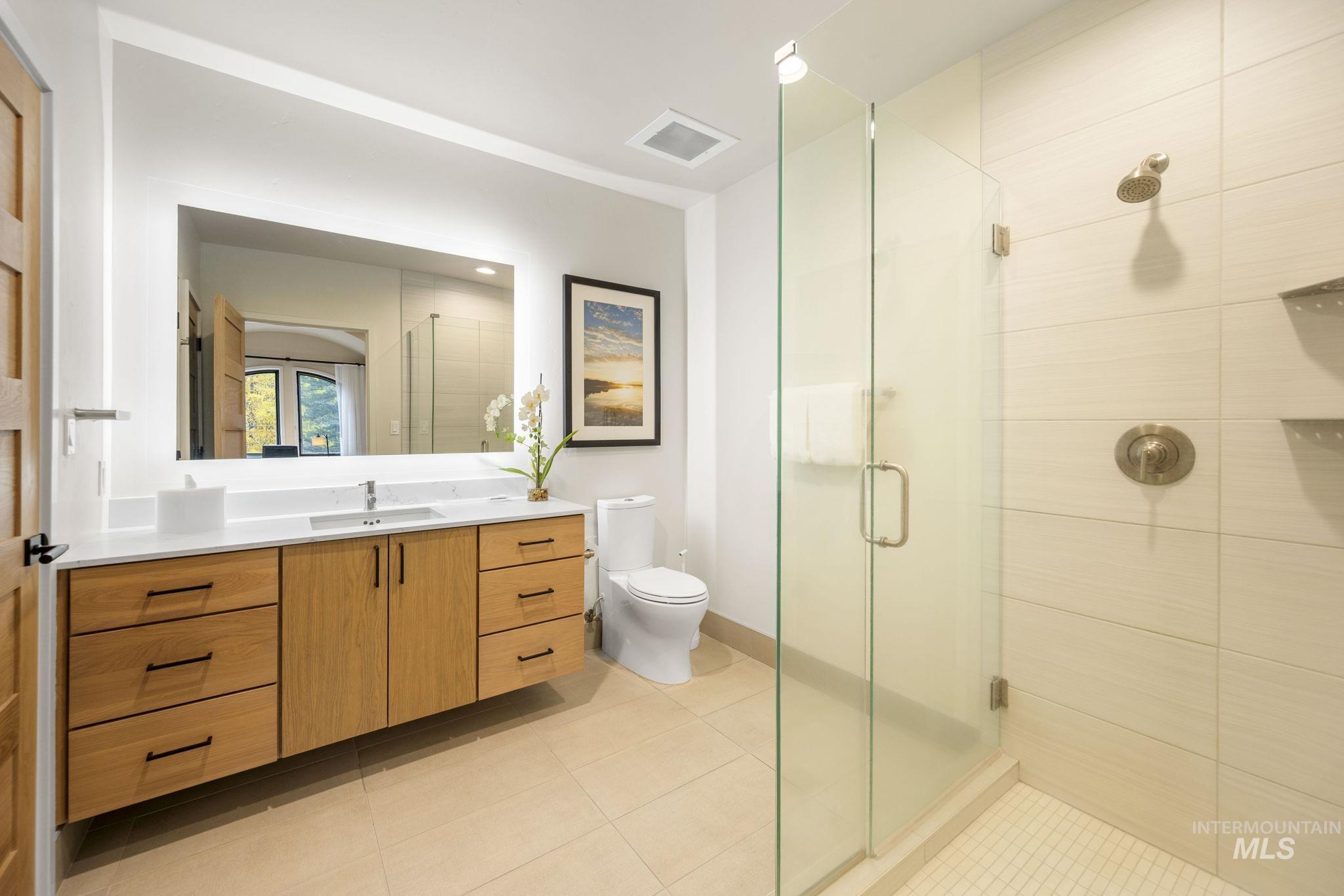 Bathroom with vanity, a shower stall, and light tile patterned floors