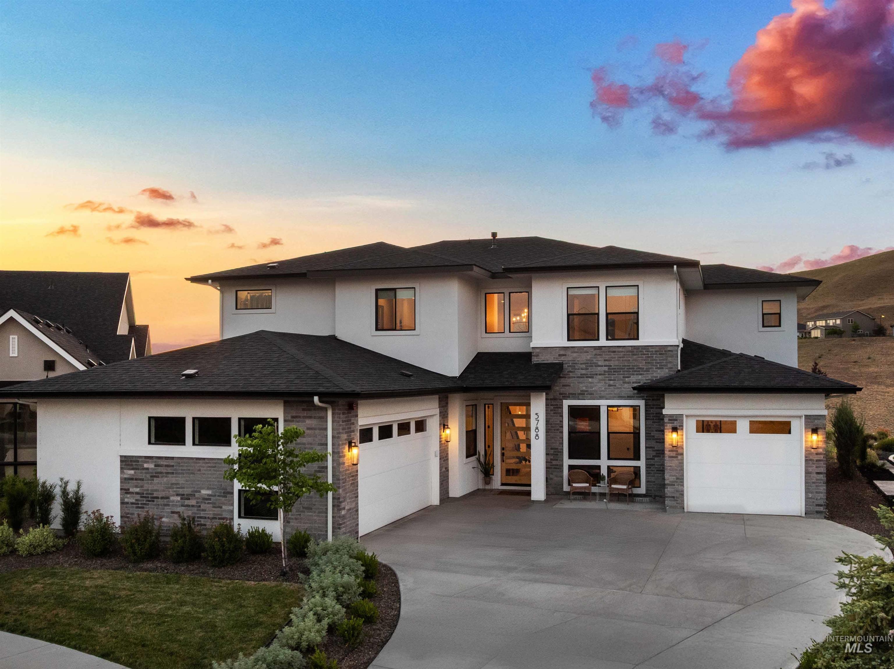 Prairie-style home featuring a garage, concrete driveway, stucco siding, and a shingled roof