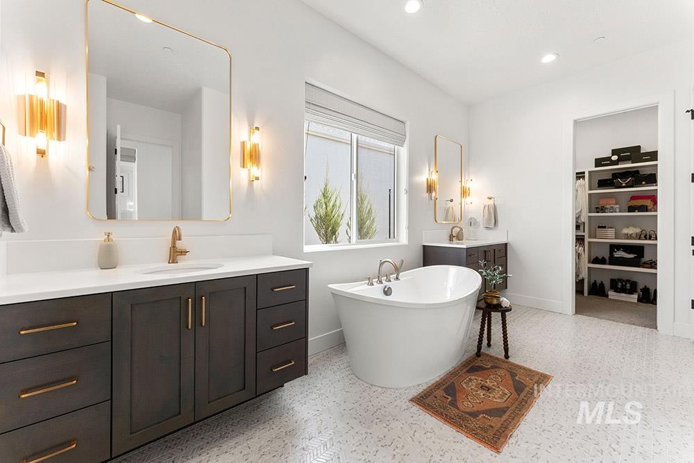 Full bath with vanity, a freestanding bath, a spacious closet, speckle patterned floor, and recessed lighting