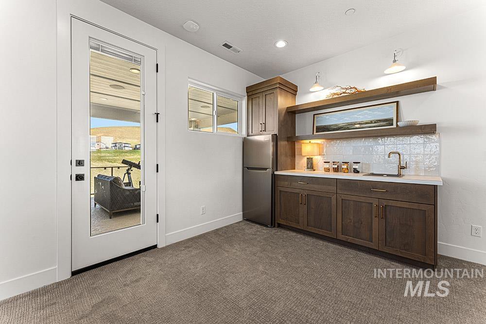 Indoor wet bar featuring freestanding refrigerator, carpet floors, and backsplash