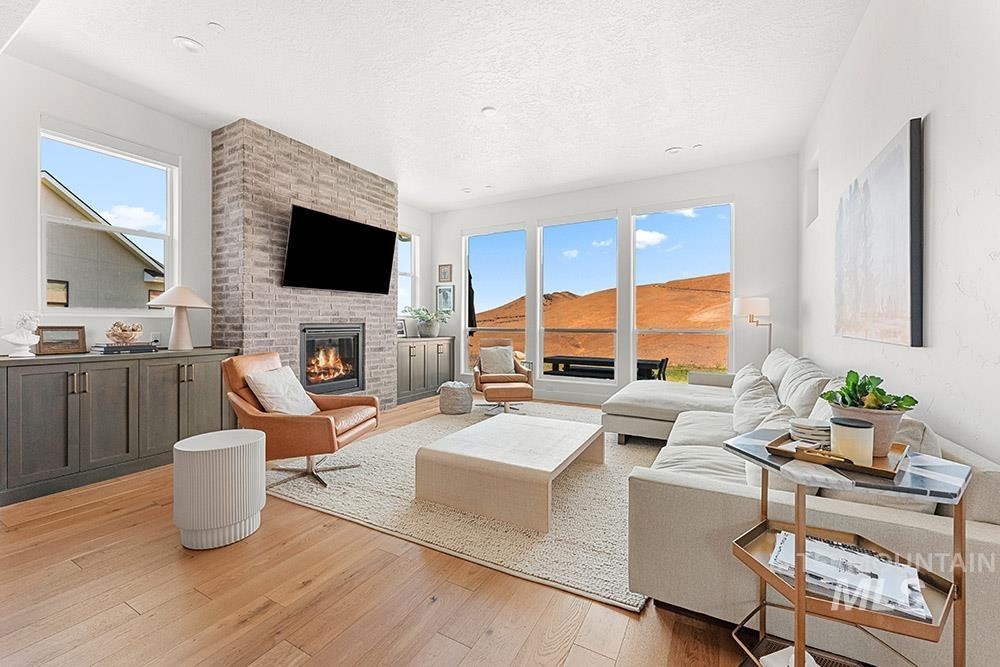 Living room with light wood finished floors, a brick fireplace, and a textured ceiling