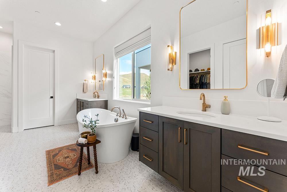Full bath with vanity, a soaking tub, recessed lighting, a spacious closet, and speckled floor