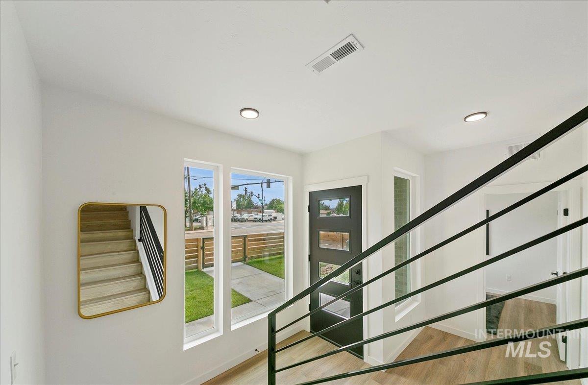 Doorway with stairs, wood finished floors, and recessed lighting