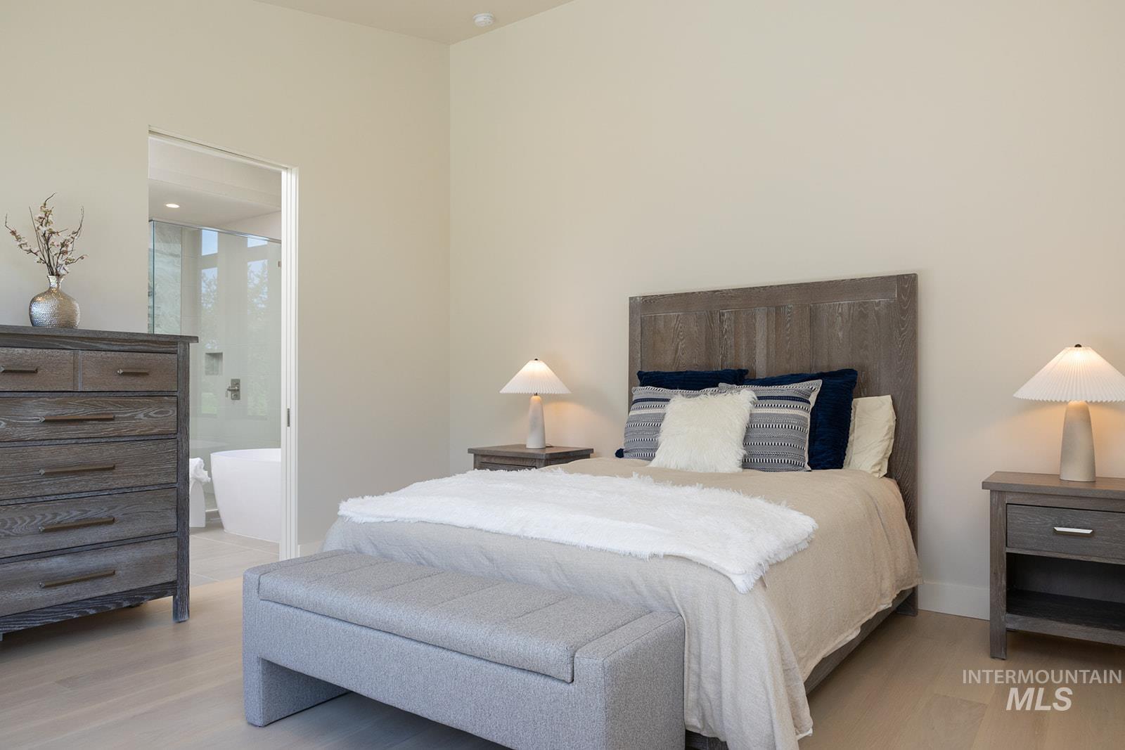 Bedroom with light wood-style flooring and ensuite bathroom
