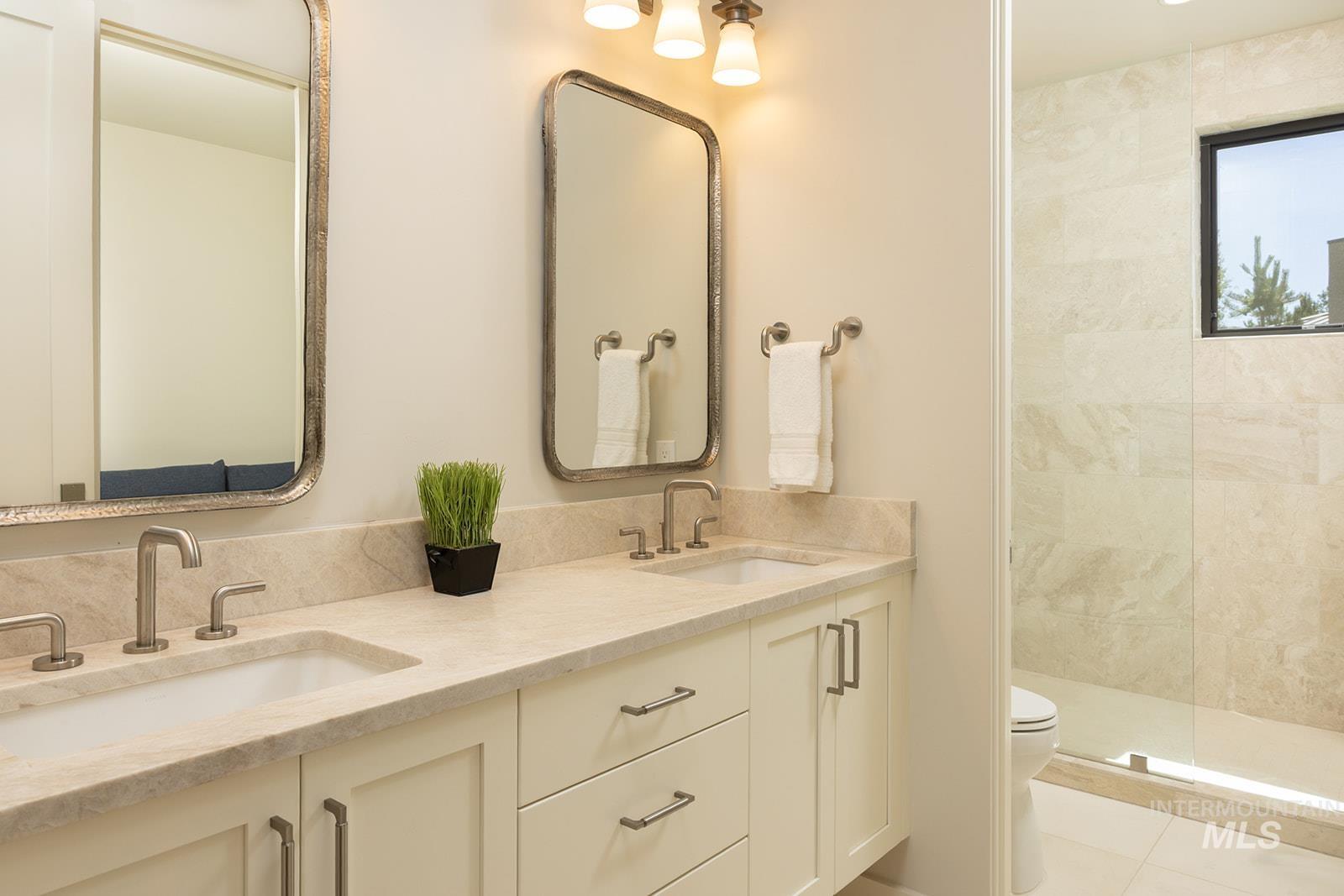 Full bathroom featuring double vanity, tiled shower, and tile patterned floors