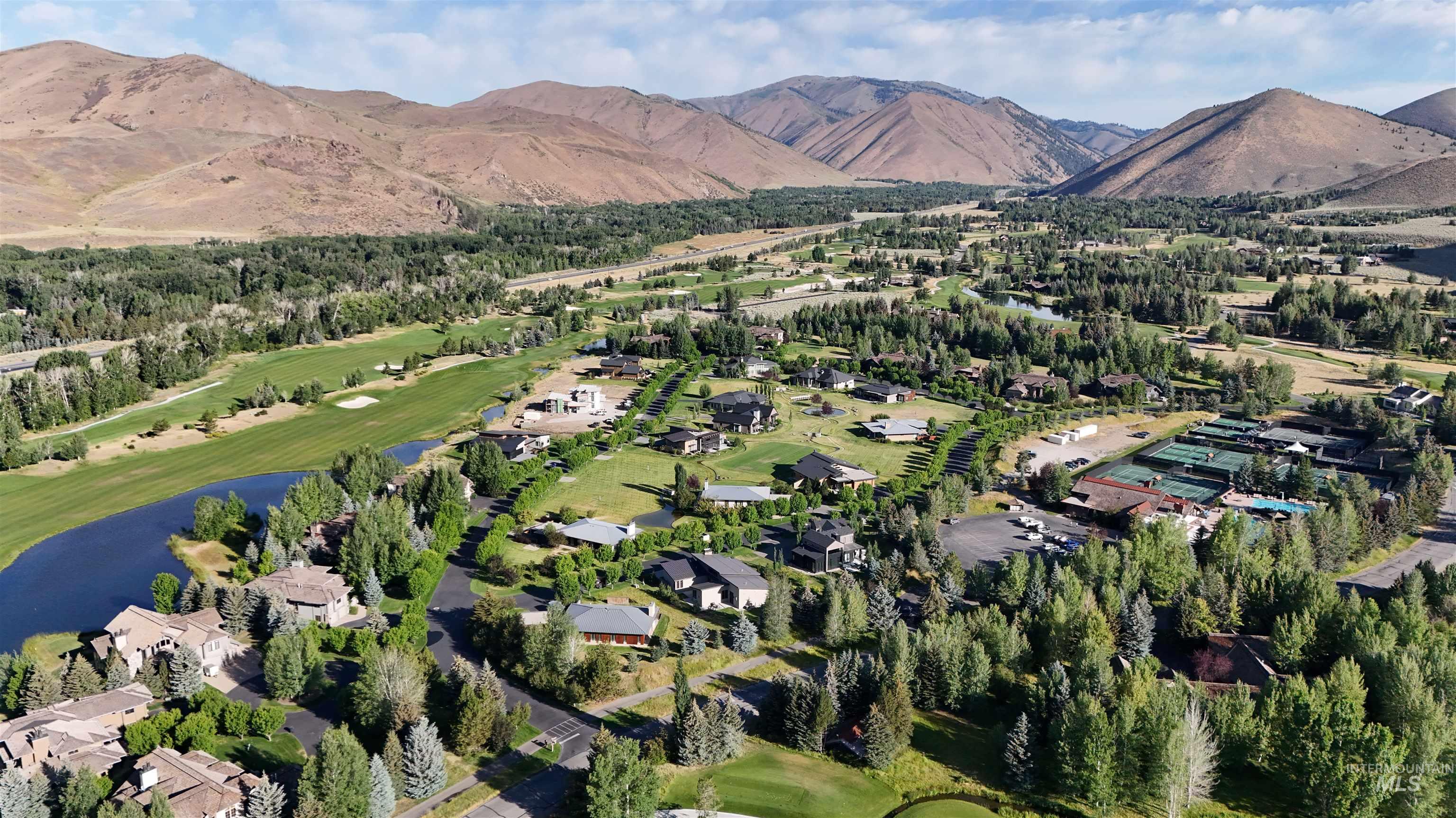 Aerial view of property's location with a golf club, a water and mountain view, and nearby suburban area