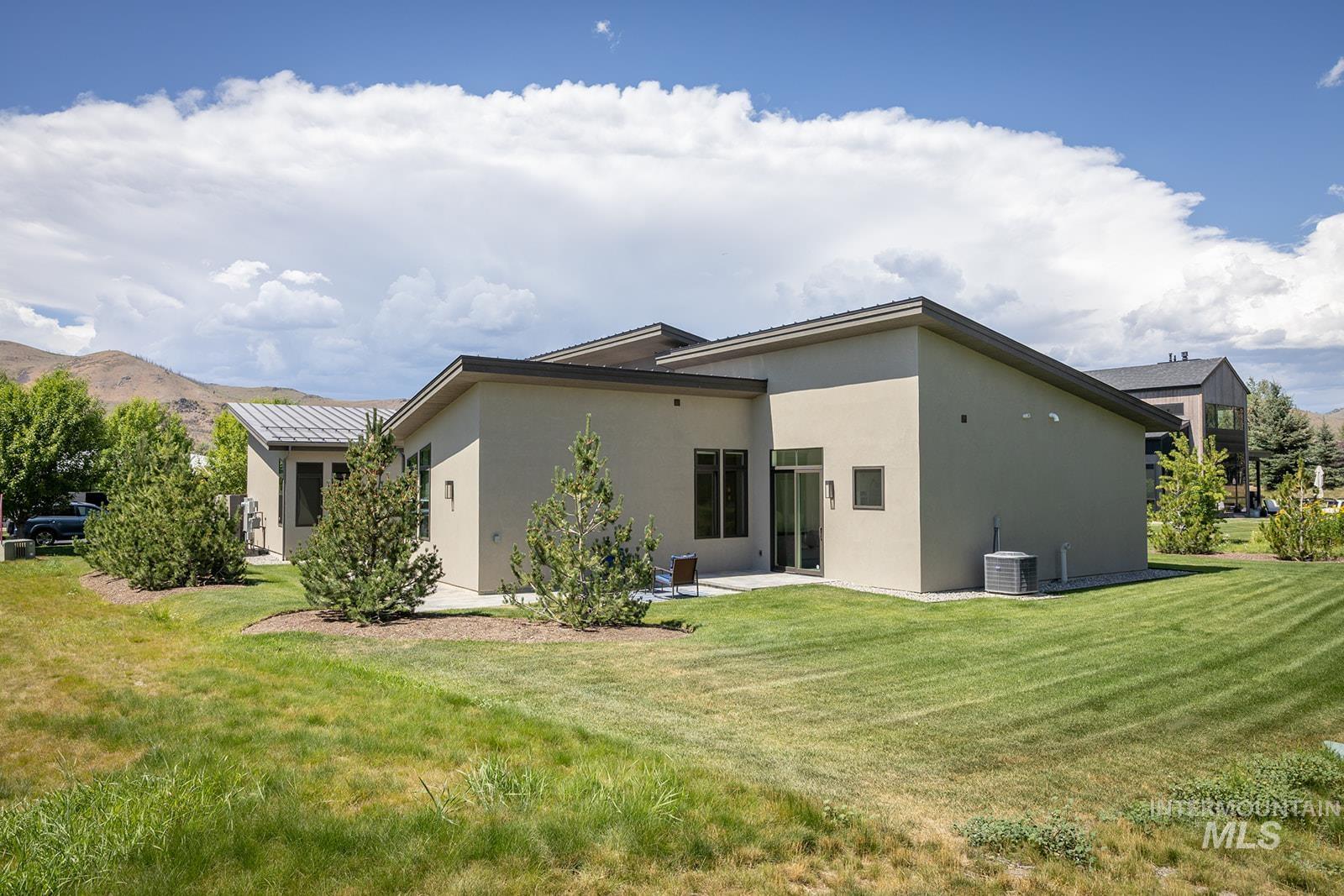 Back of property featuring stucco siding, a lawn, and a patio area