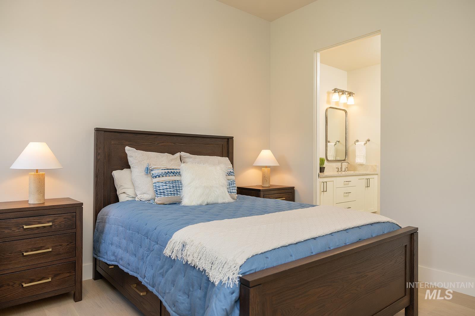 Bedroom featuring ensuite bathroom and light wood-style flooring
