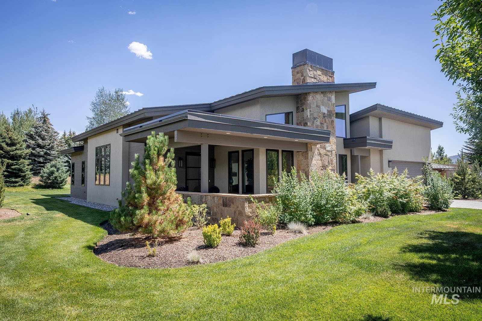 View of side of property with stone siding, a lawn, stucco siding, and a chimney