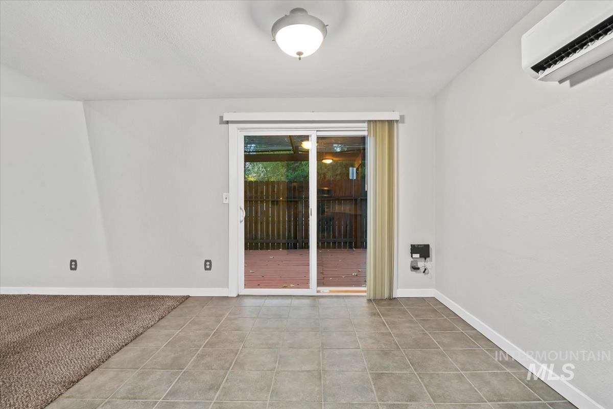 Spare room featuring a wall mounted AC, light colored carpet, and light tile patterned floors