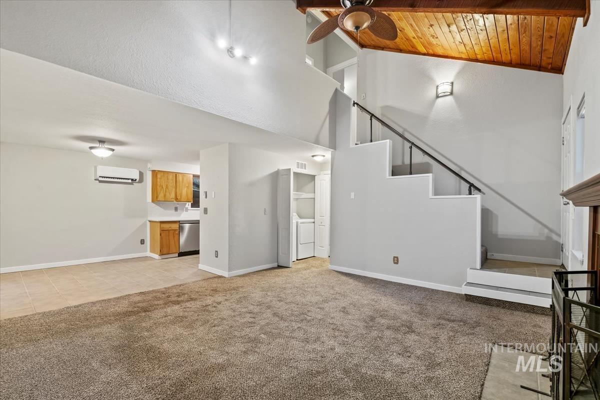 Unfurnished living room with light colored carpet, high vaulted ceiling, an AC wall unit, wooden ceiling, and light tile patterned flooring
