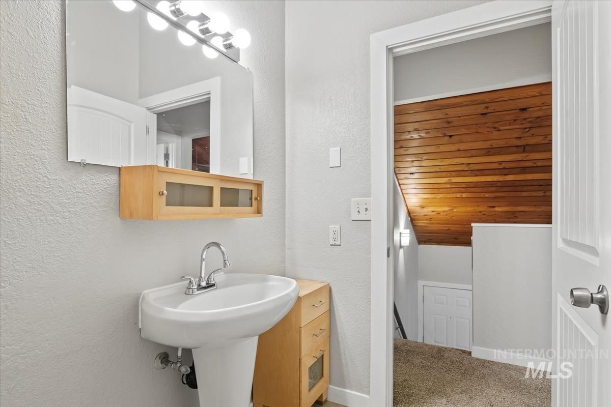 Bathroom with a textured wall and light colored carpet