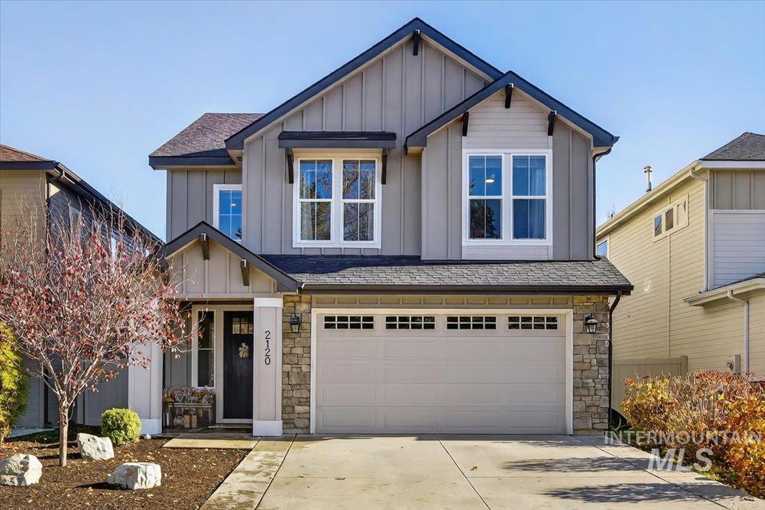 Craftsman-style home with board and batten siding, stone siding, an attached garage, and driveway