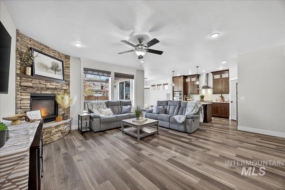 Living area featuring dark wood-style flooring, a ceiling fan, a fireplace, a textured ceiling, and recessed lighting