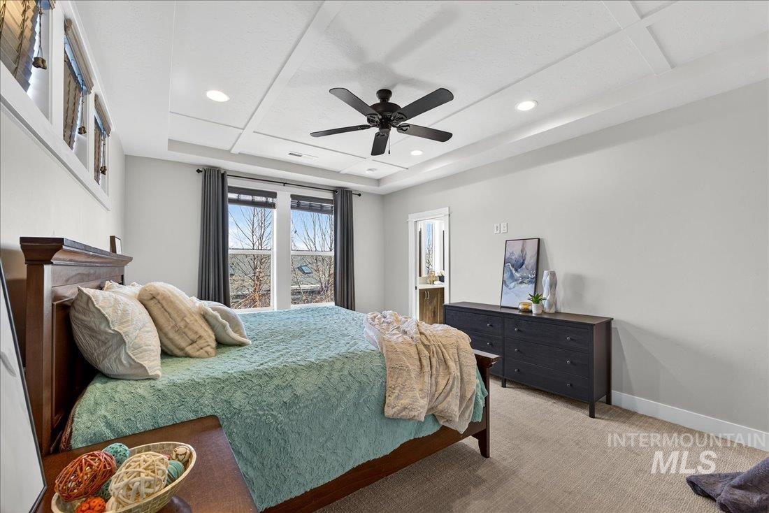 Carpeted bedroom with ceiling fan, recessed lighting, and a tray ceiling