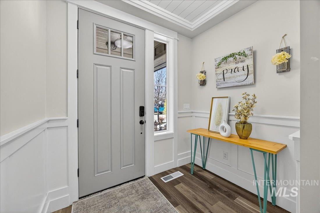 Foyer with a decorative wall, a wainscoted wall, and dark wood-style flooring