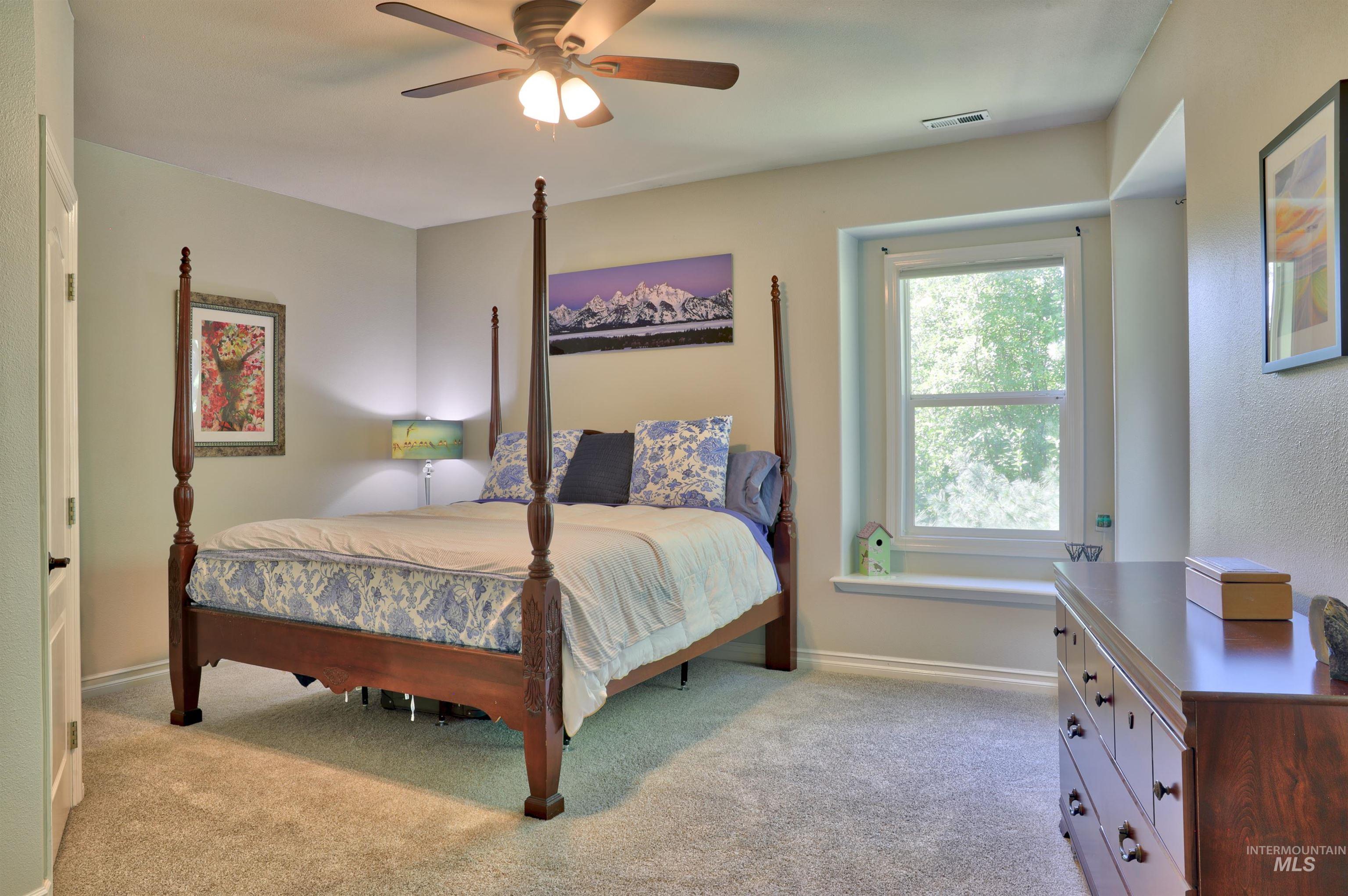 Carpeted interior space featuring a window with a deep sill, a ceiling fan with integrated lighting, and a white interior door