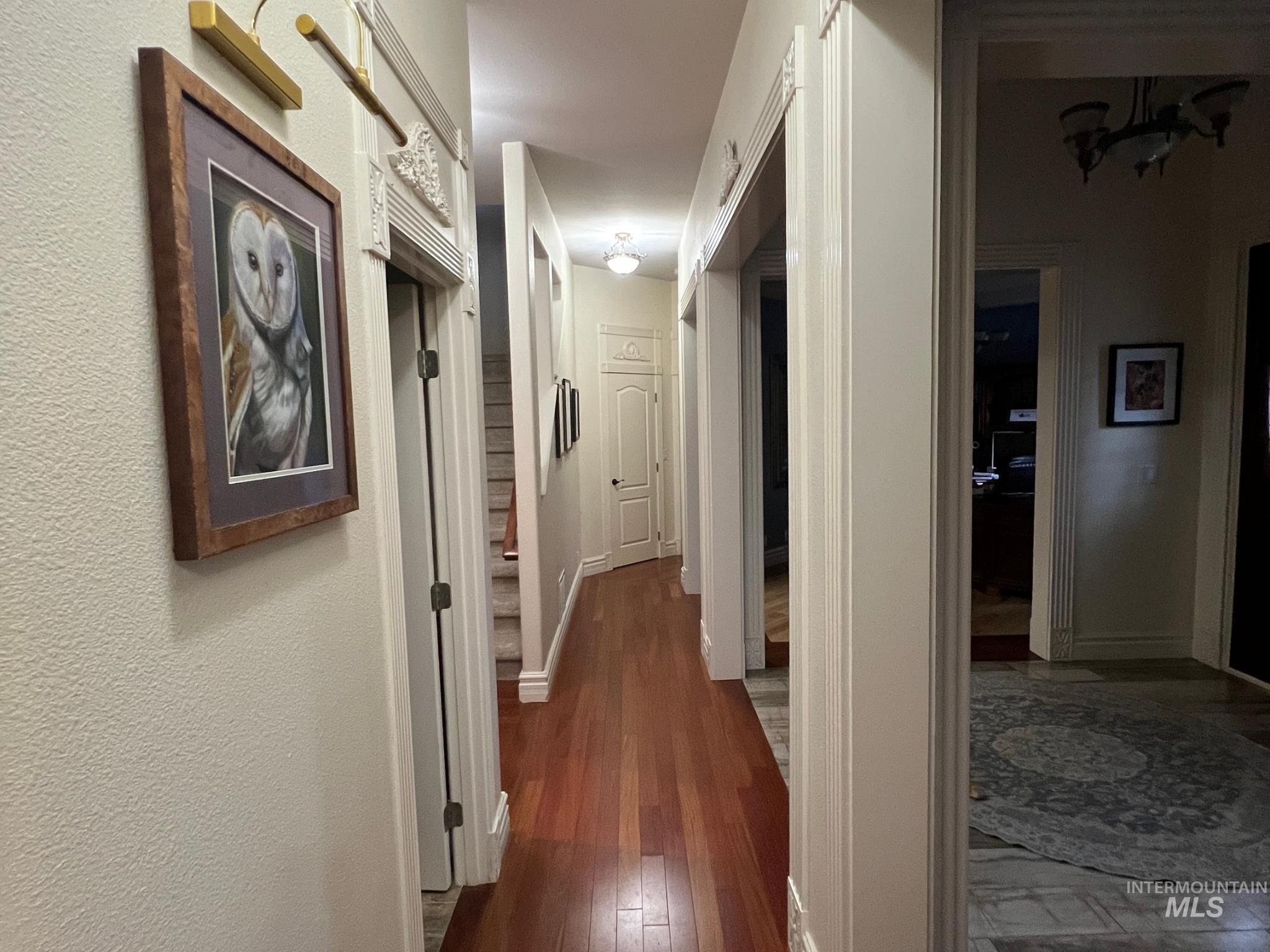 Hallway with wood-finish flooring, textured wall finishes, and decorative door trim