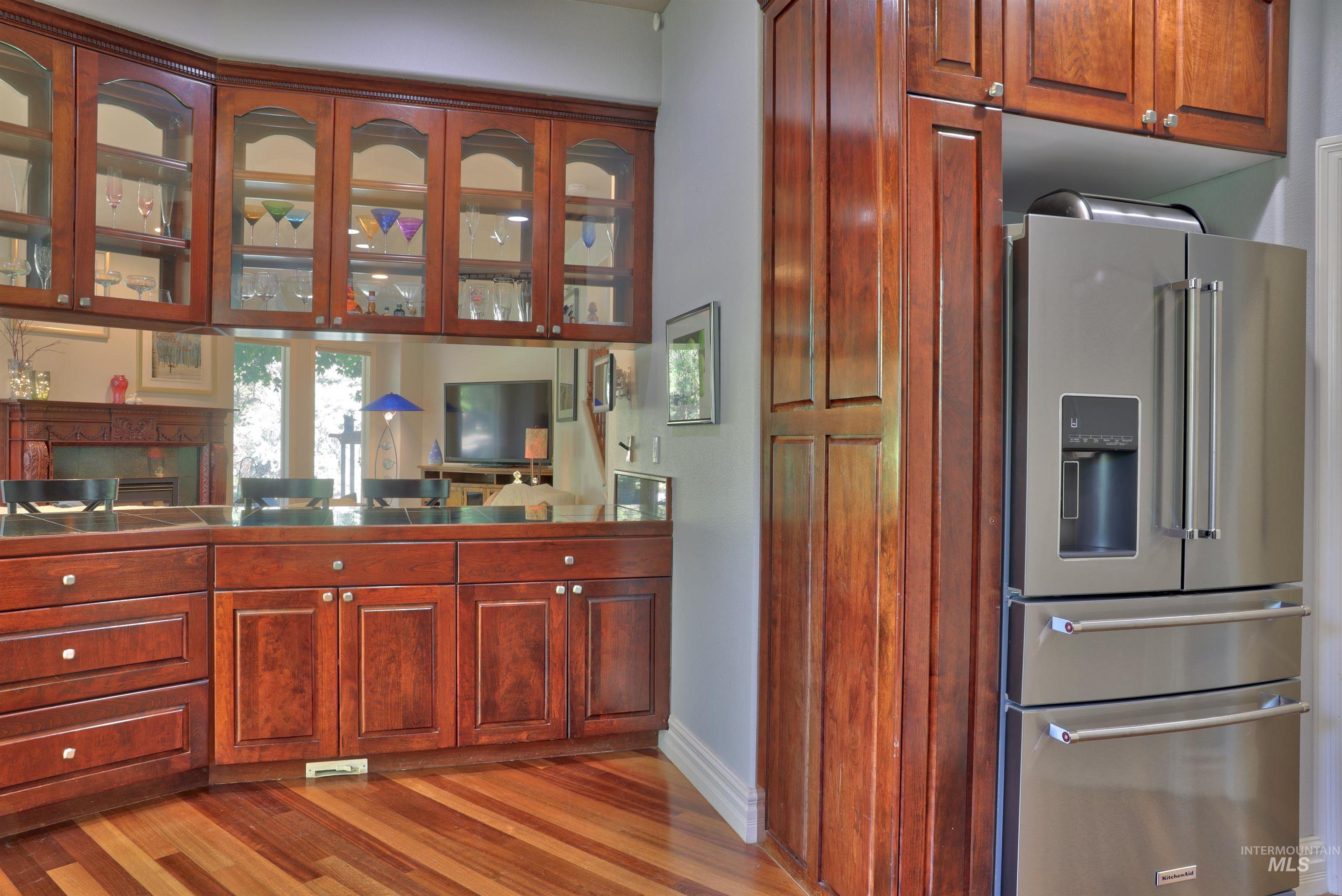 Rich wood-finish cabinetry with glass-front upper units and mirrored backsplash