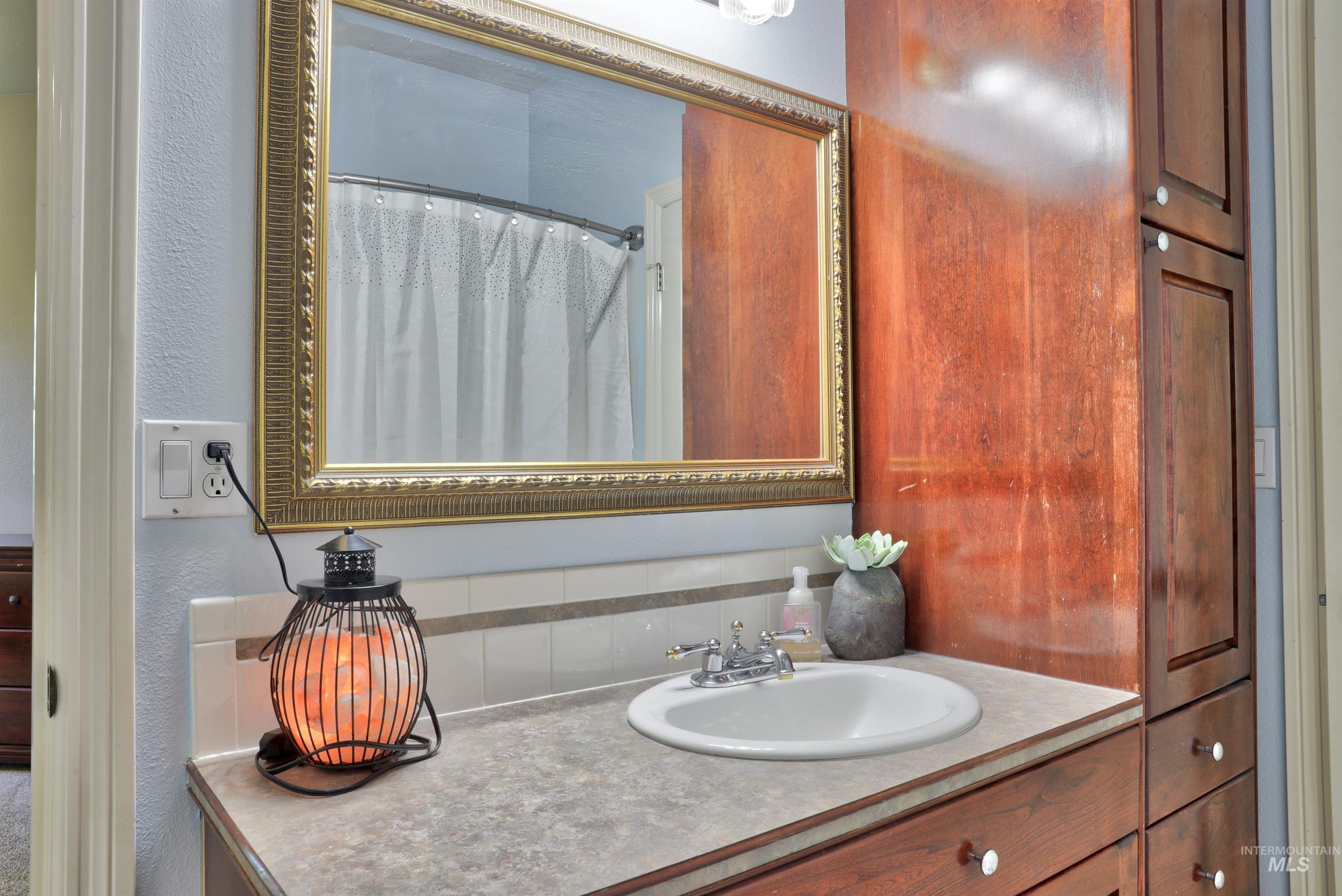 Bathroom vanity featuring a drop-in sink with chrome faucet, light-colored countertop, and a large decorative mirror