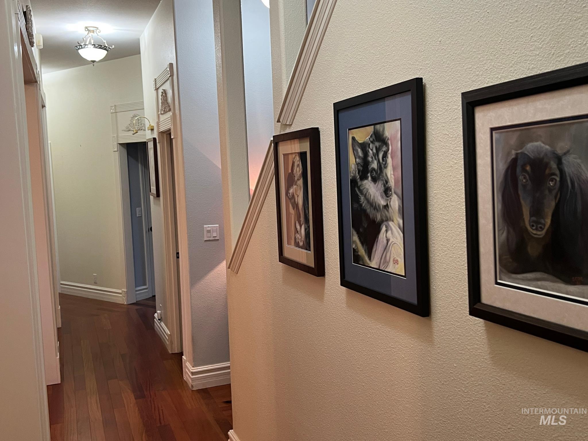 Hallway featuring wood-finish flooring, white baseboards, and a decorative ceiling light fixture