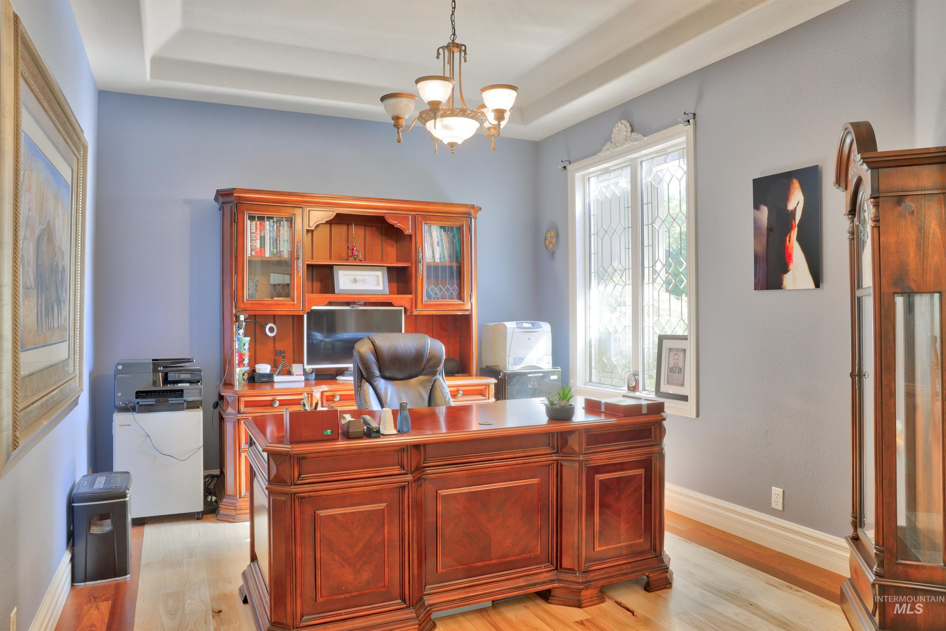 Dedicated office space featuring wood-finish flooring, a coffered ceiling, and a decorative chandelier