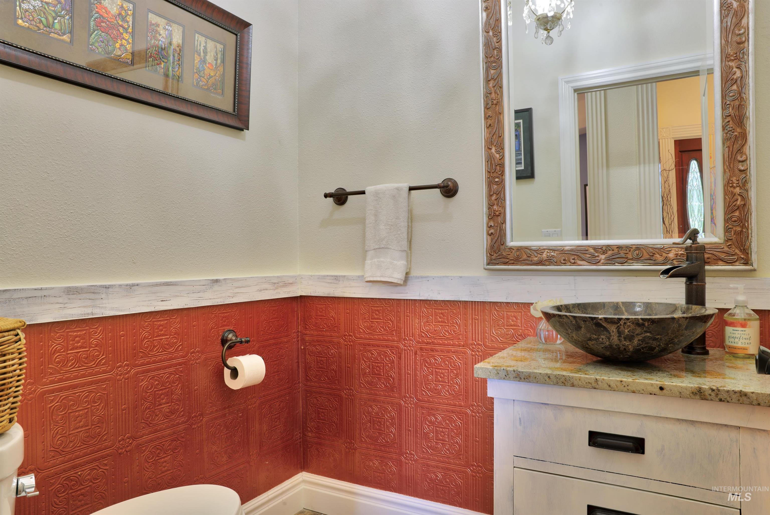 Vanity featuring a vessel sink, stone countertop, and carved wood-finish mirror frame