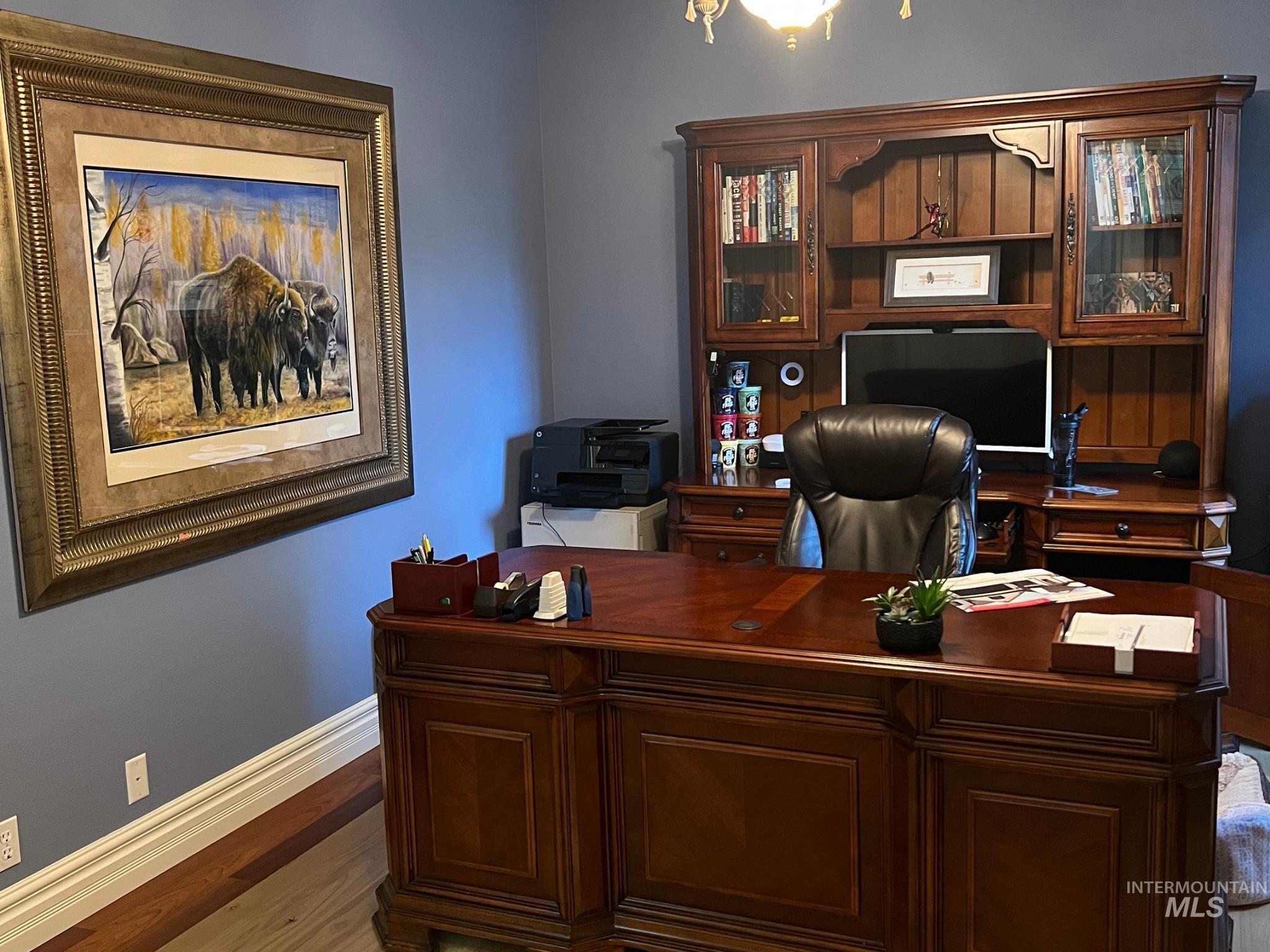 Rich wood-finish desk featuring intricate paneling and a built-in hutch with glass-fronted cabinetry